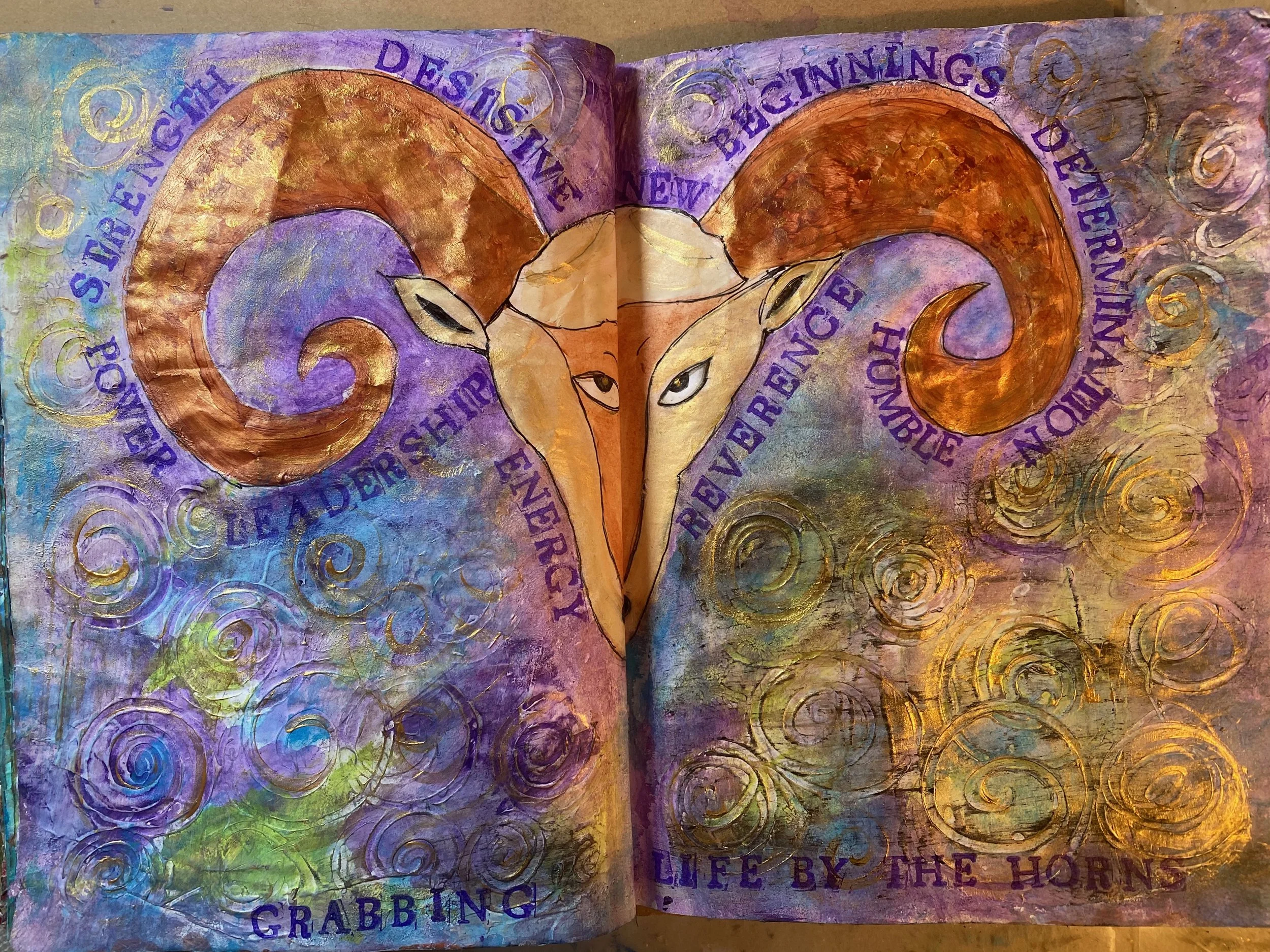 A mixed media artwork with vibrant colors and swirling patterns, featuring text and an abstract illustration of a goat or ram with prominent horns. The text includes phrases like 'des is the glorious day,' 'life by the horn,' and other partial phrase