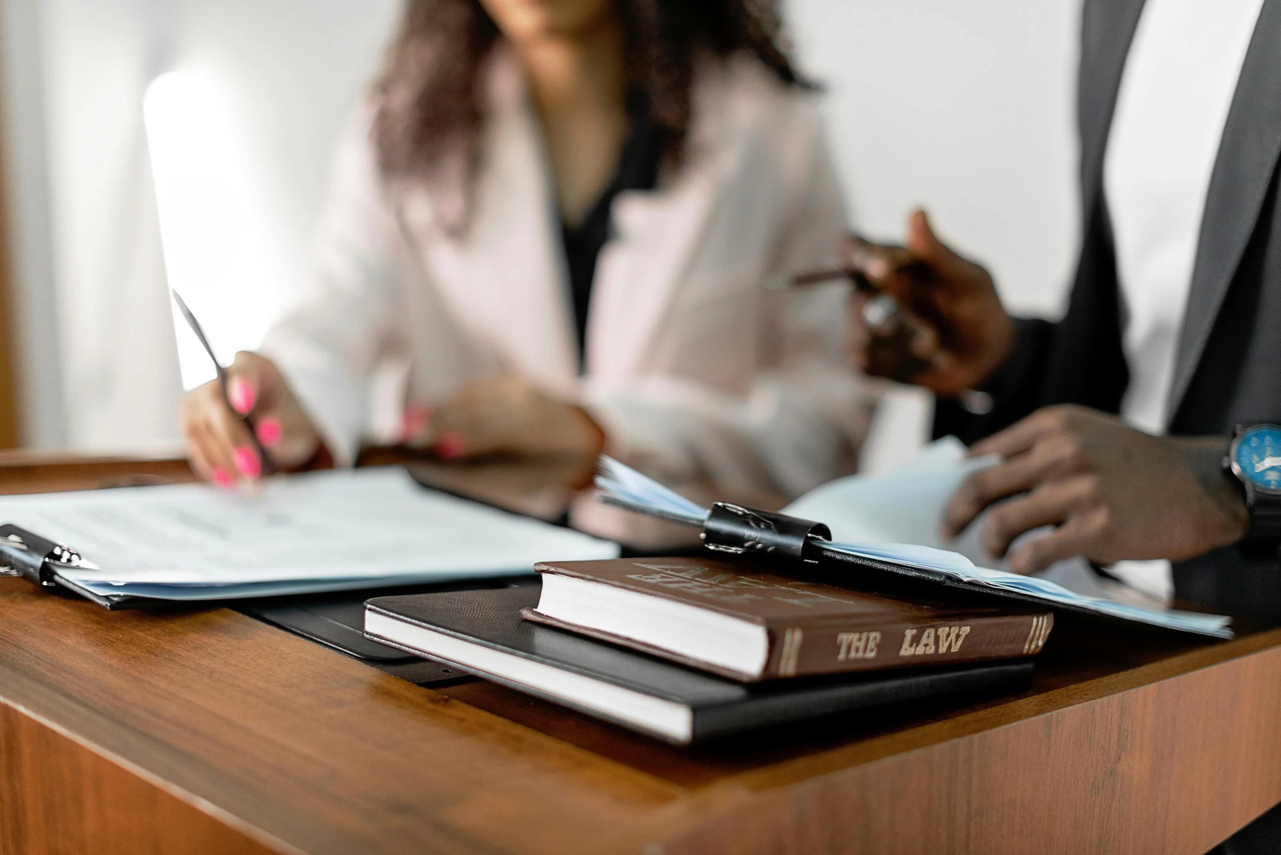 People discussing or working on legal documents at a wooden table, with books and notebooks about law.