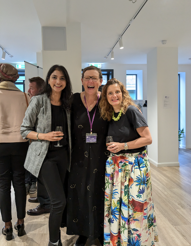 Three ladies standing and laughing together at event