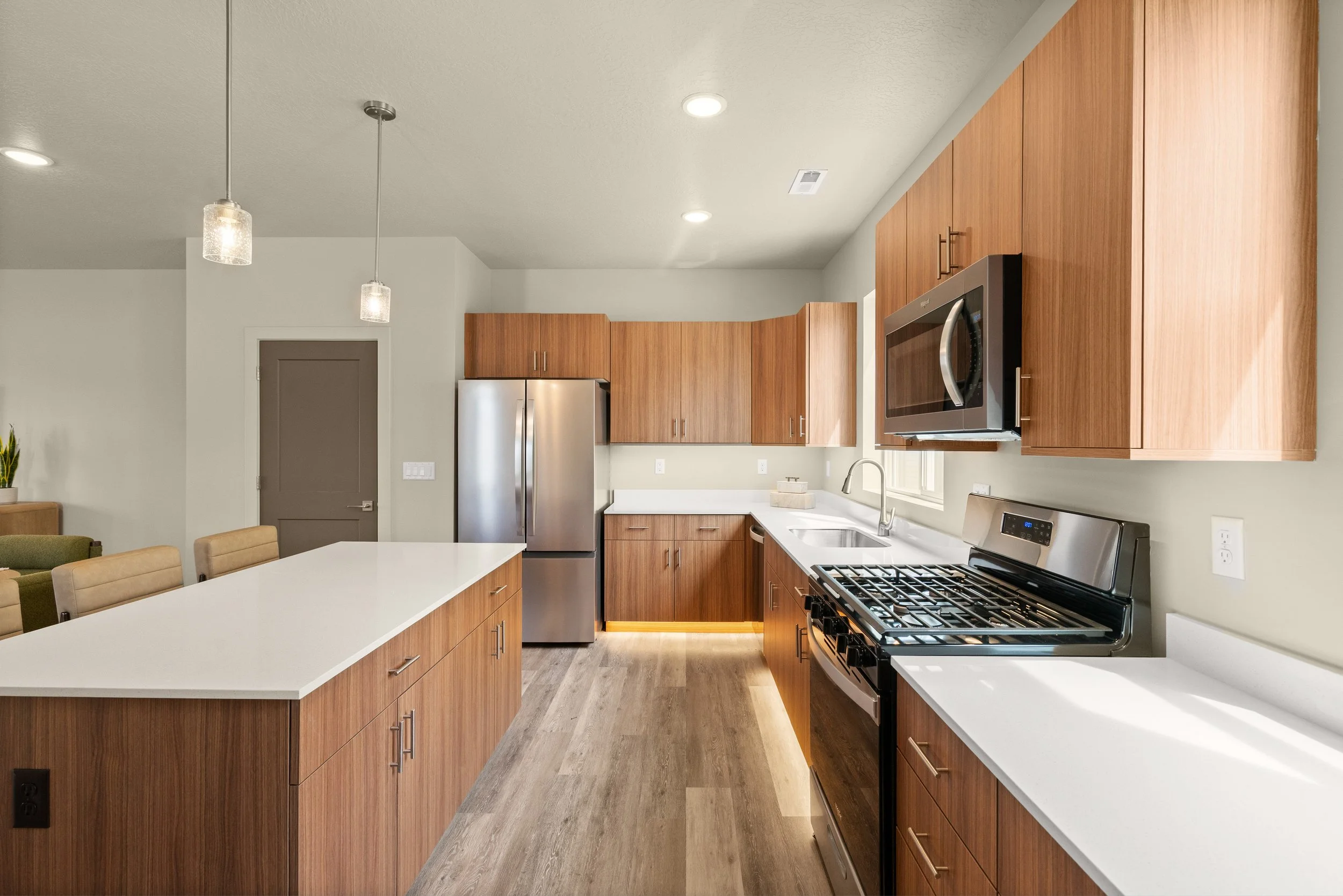 Modern kitchen with wooden cabinets, stainless steel appliances, white countertop, and hardwood flooring.