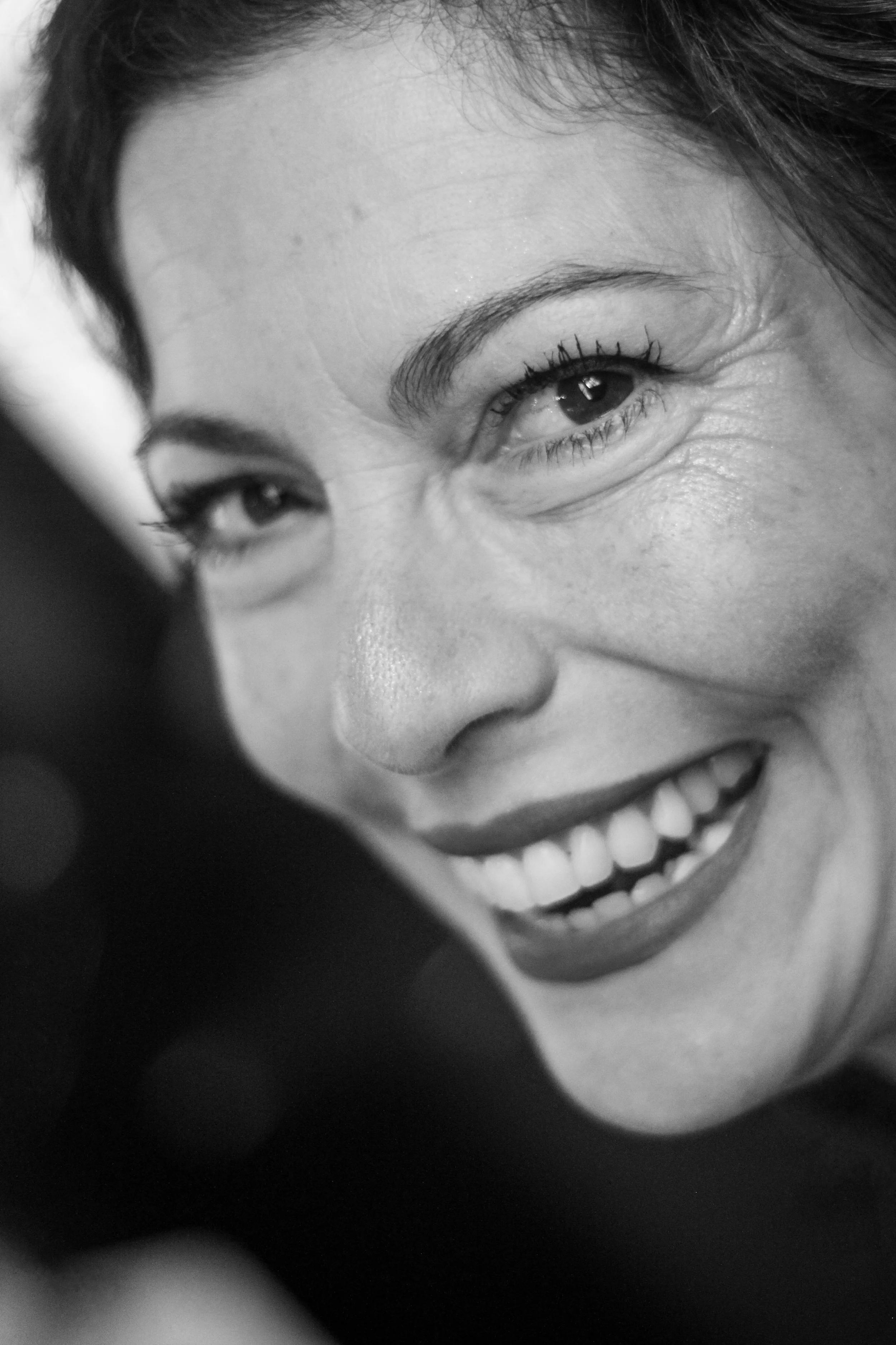 Close-up black and white photo of Vera Soublechero, the creator of the community OTG and author of: Only a Tour Guide Can Tell You. She is smiling, looking aprochabe, friendly, bolt
