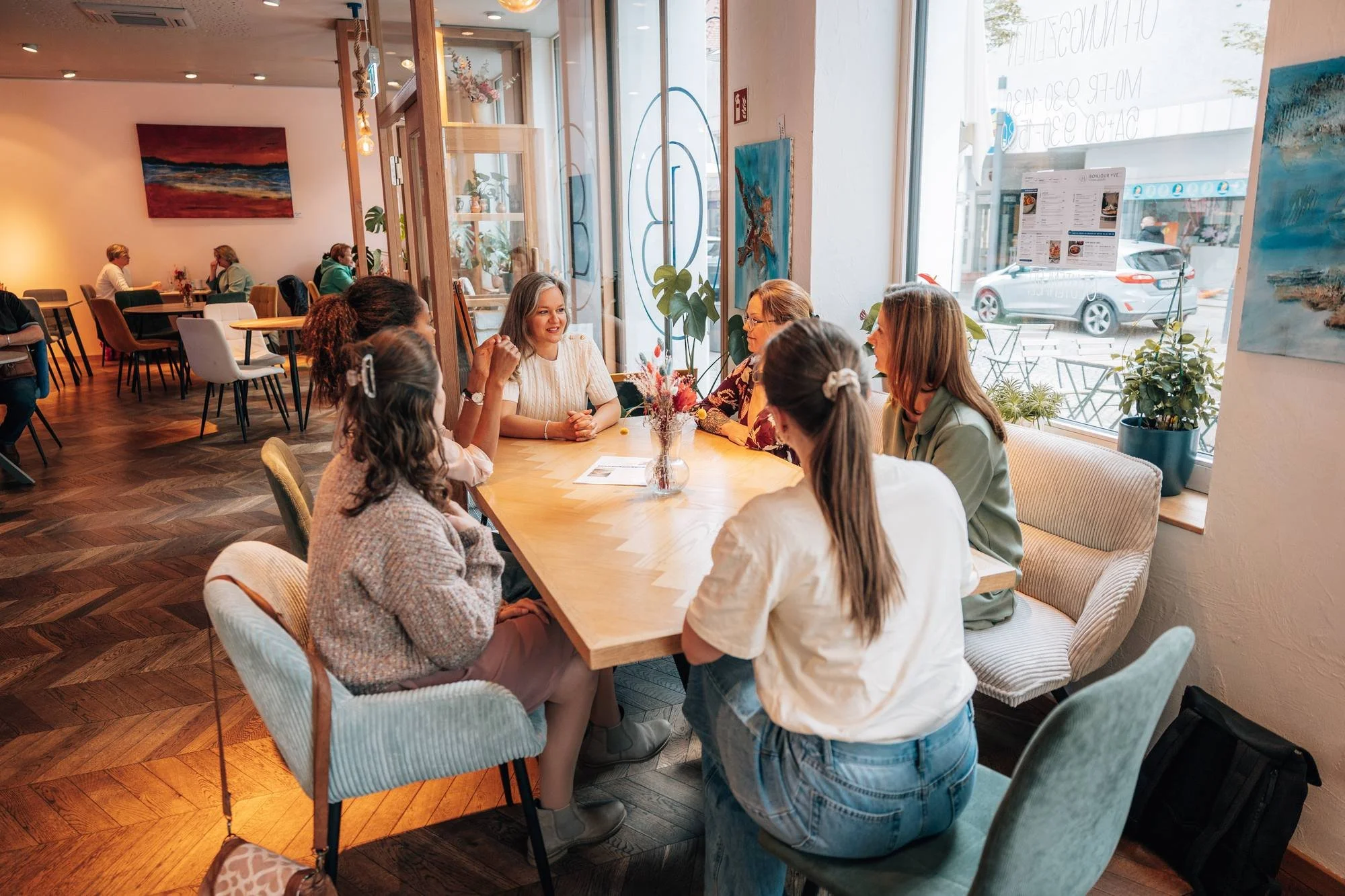 Frauen sitzen bei Coffee & Grow gemeinsam an einem langen Tisch im Café