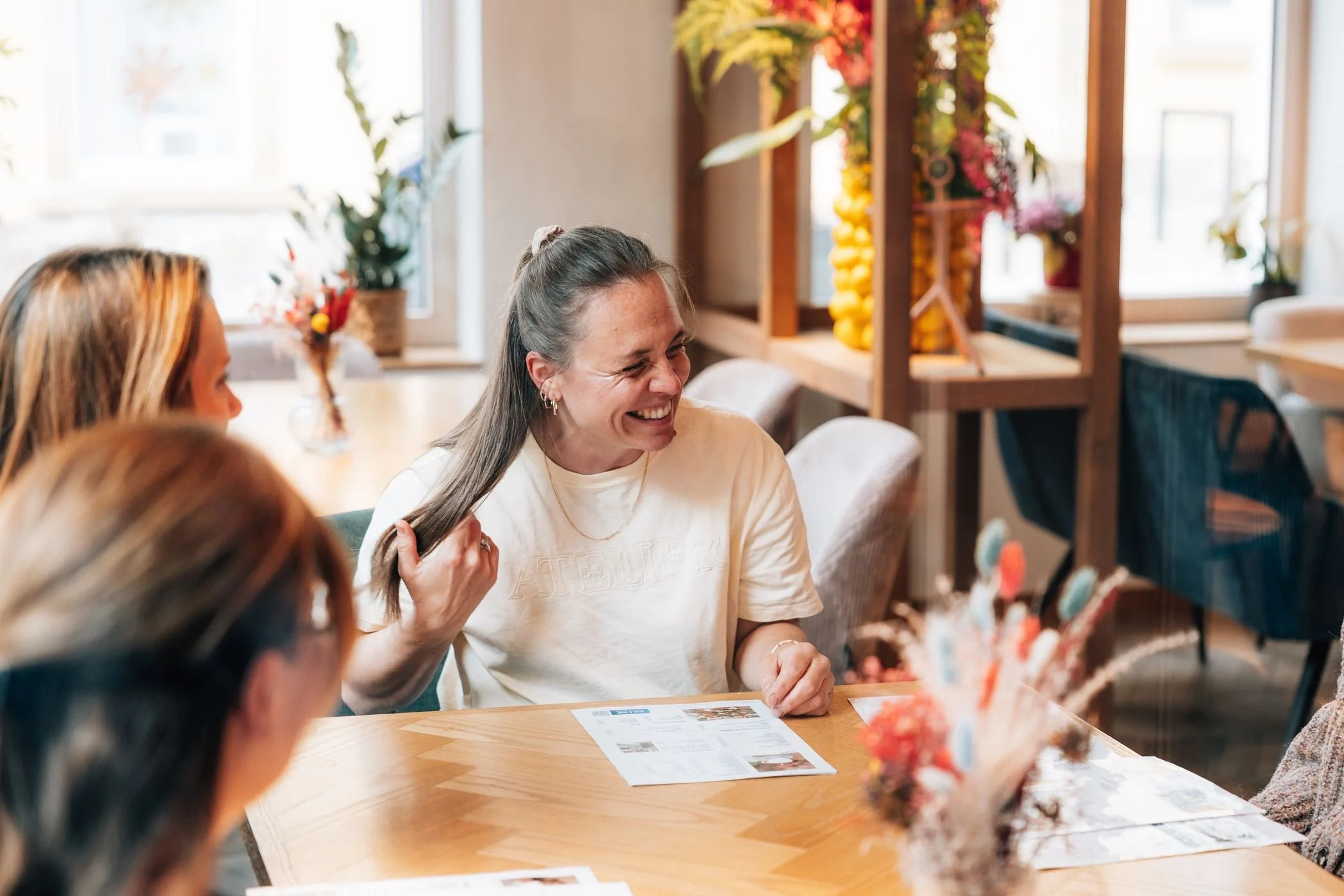 Eine Frau lacht herzlich bei Coffee & Grow am Cafétisch