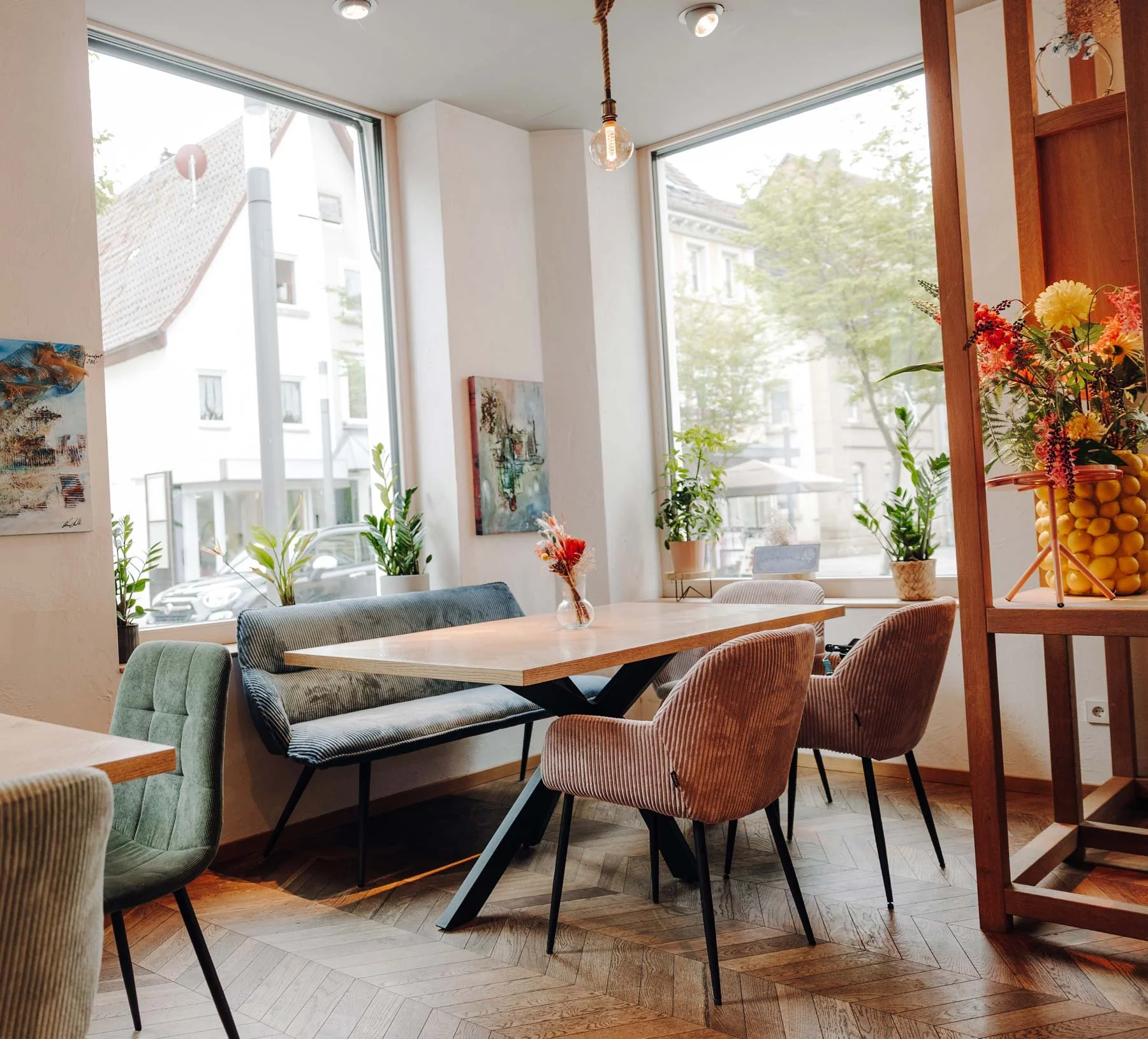 Ein gemütliches Café mit bunten Möbeln, Holztischen und Pflanzen.