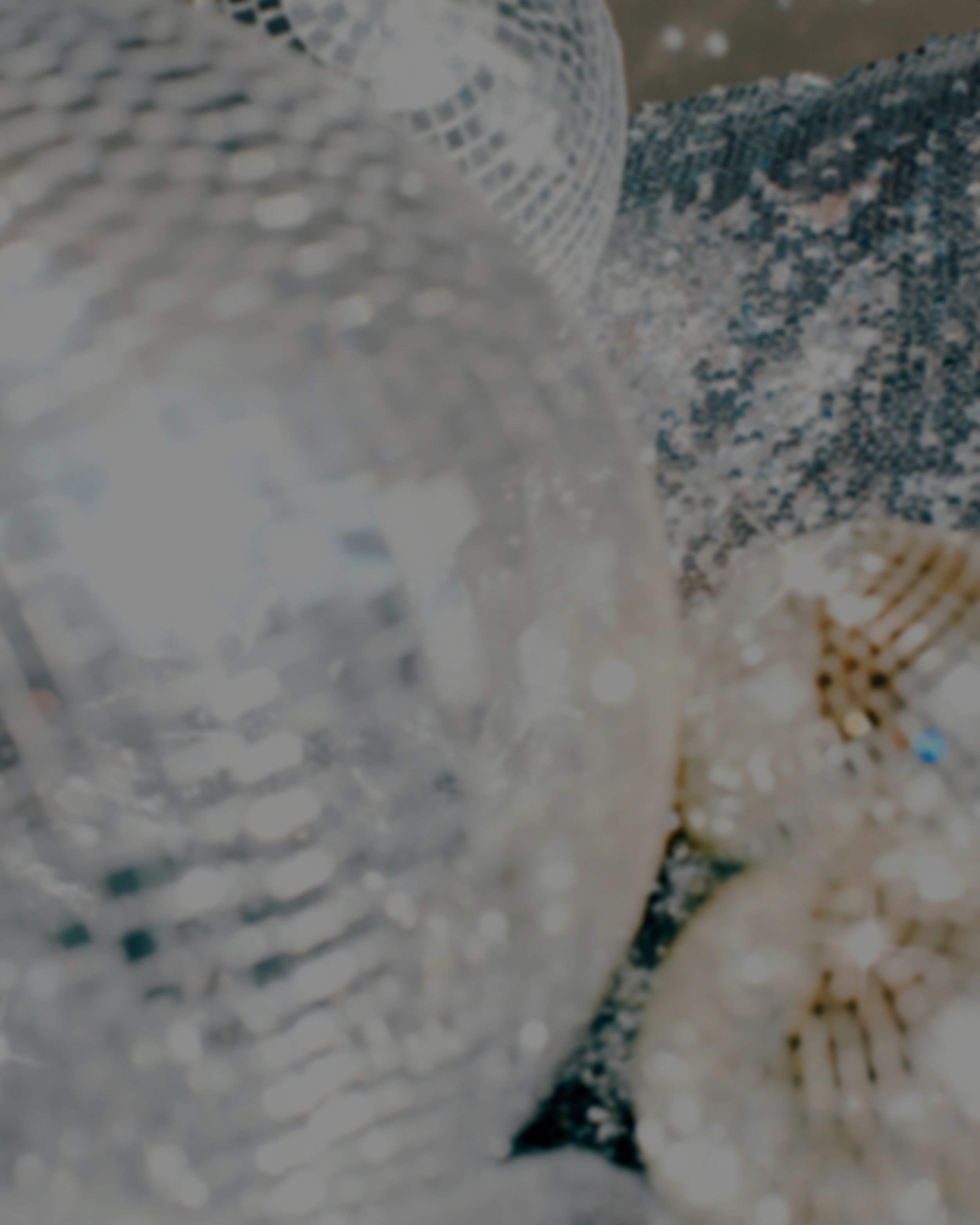Close-up of shiny, reflective disco balls with a patterned cloth in the background.