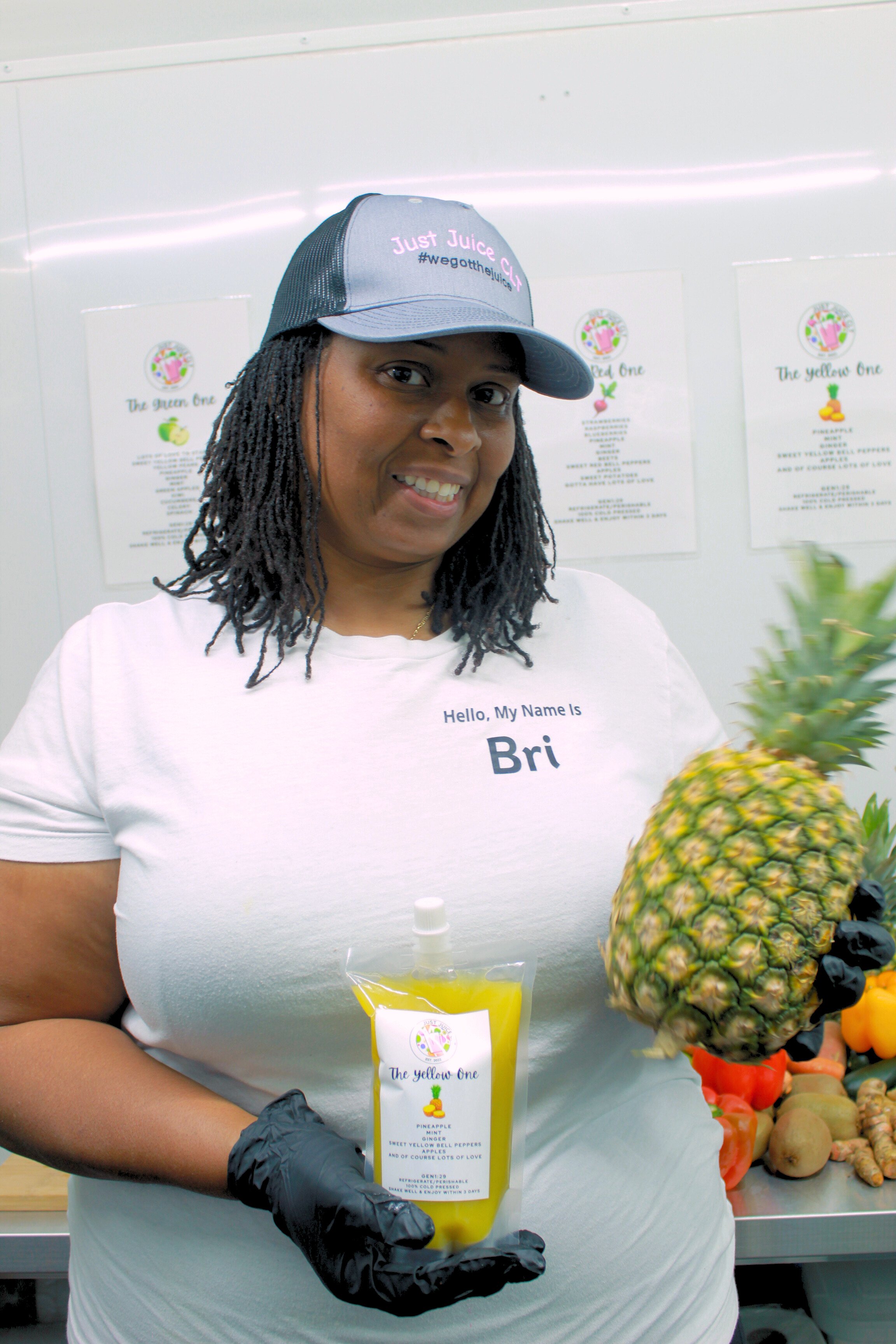 Co-Owner from Just Juice CLT holding "The Yellow One" cold-pressed juice made with fresh pineapple and other natural ingredients.