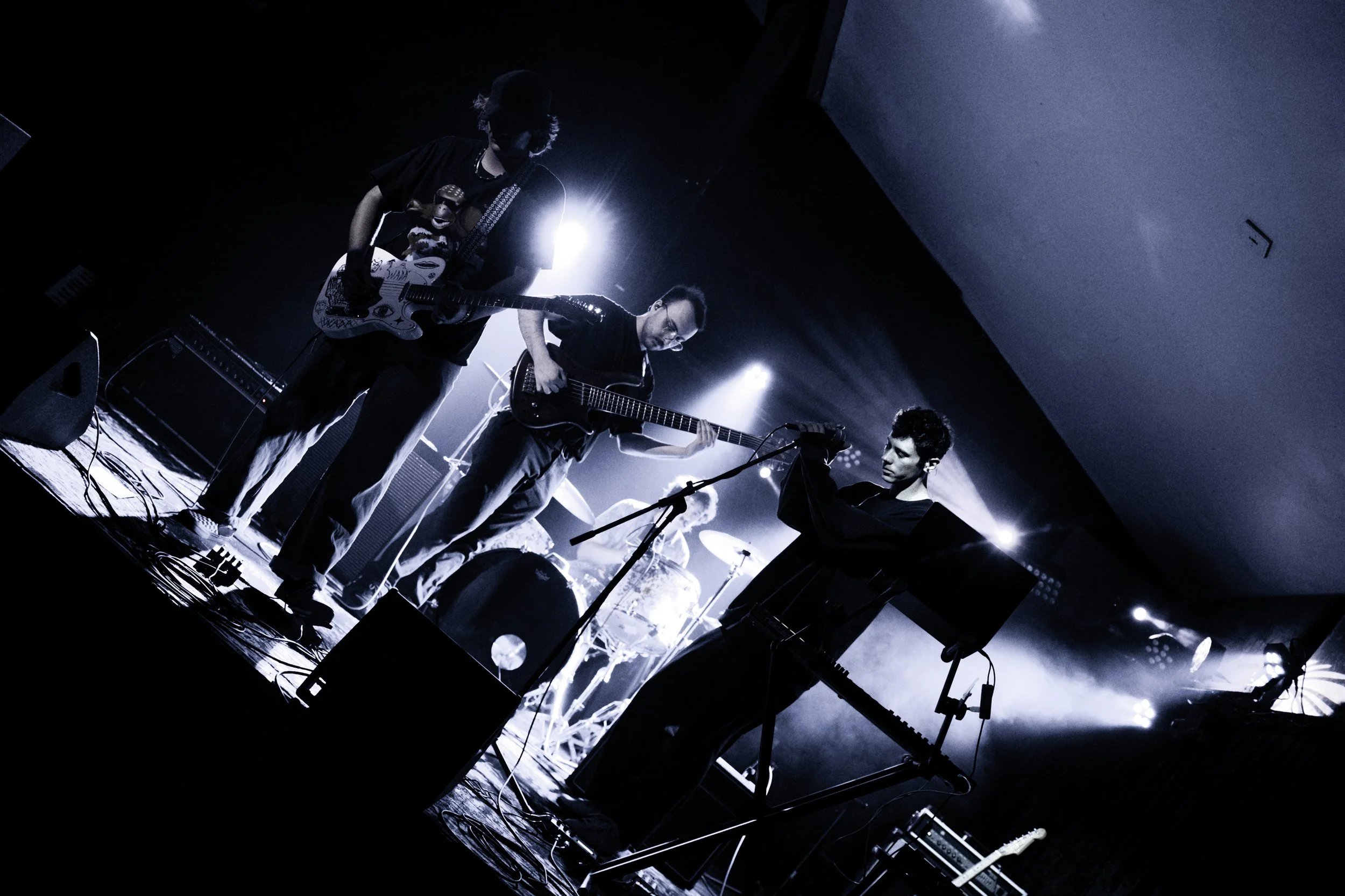 Musicians performing on stage with guitars, under dramatic lighting.