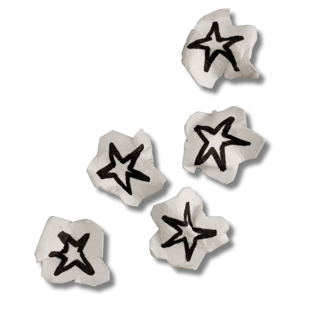 Five crumpled white paper pieces with black star drawings scattered on a black background.