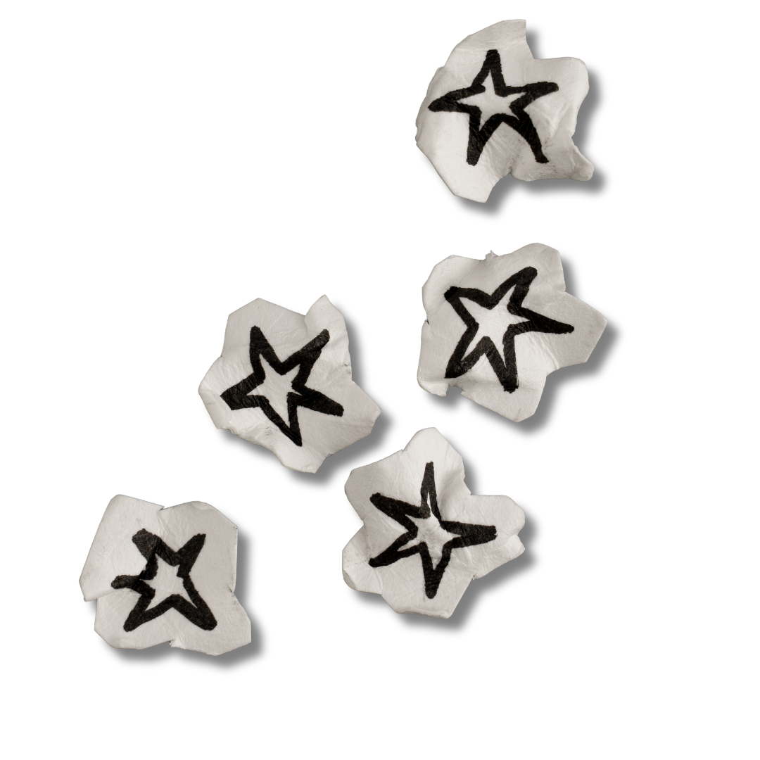 Five white star-shaped candies with black star outlines on a black background.