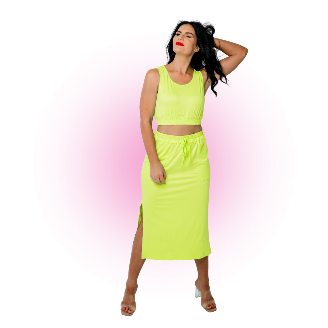 Woman in yellow crop top and skirt with pink background
