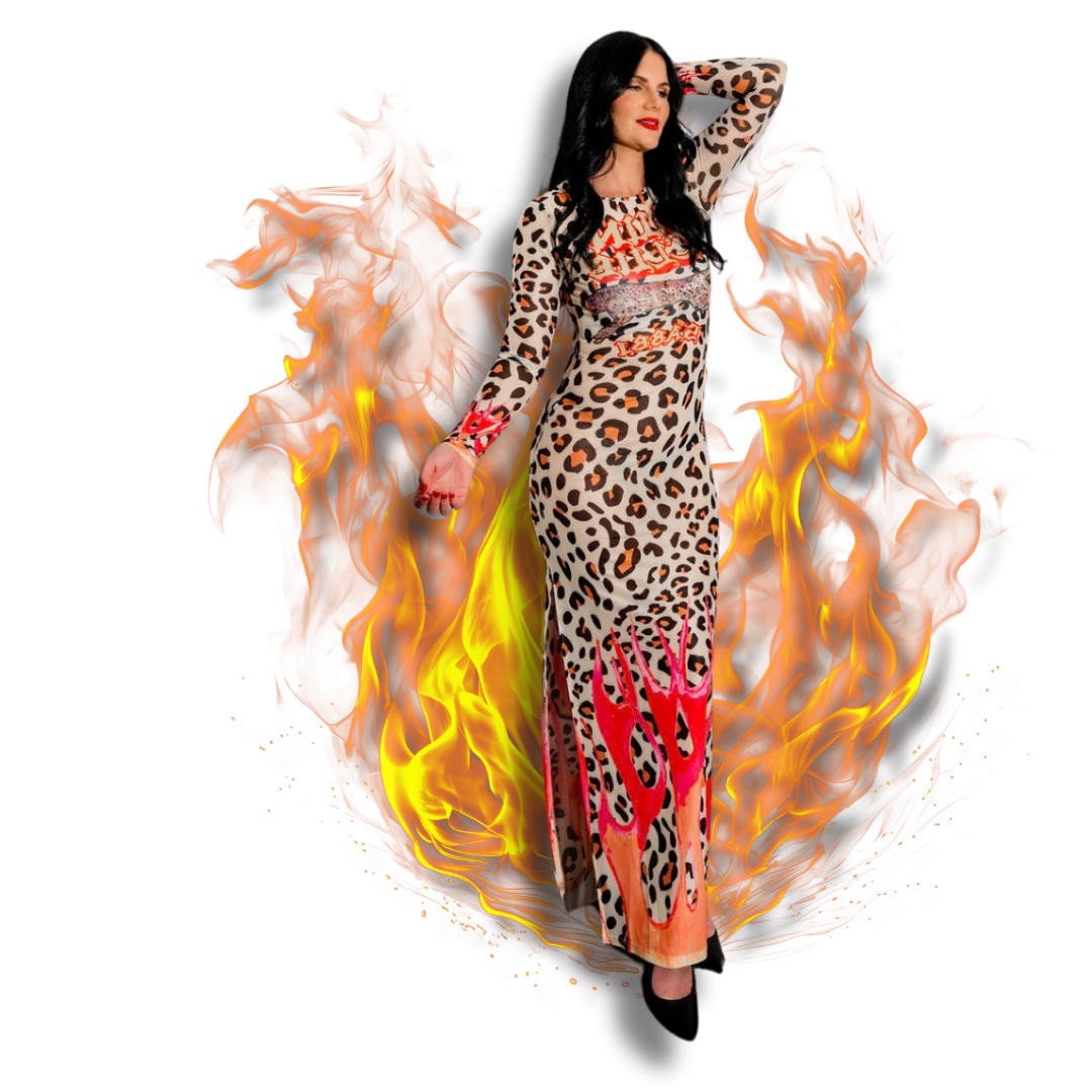 A woman in a long leopard print dress with red accents, standing amidst flames, with her hand behind her head and a confident expression.