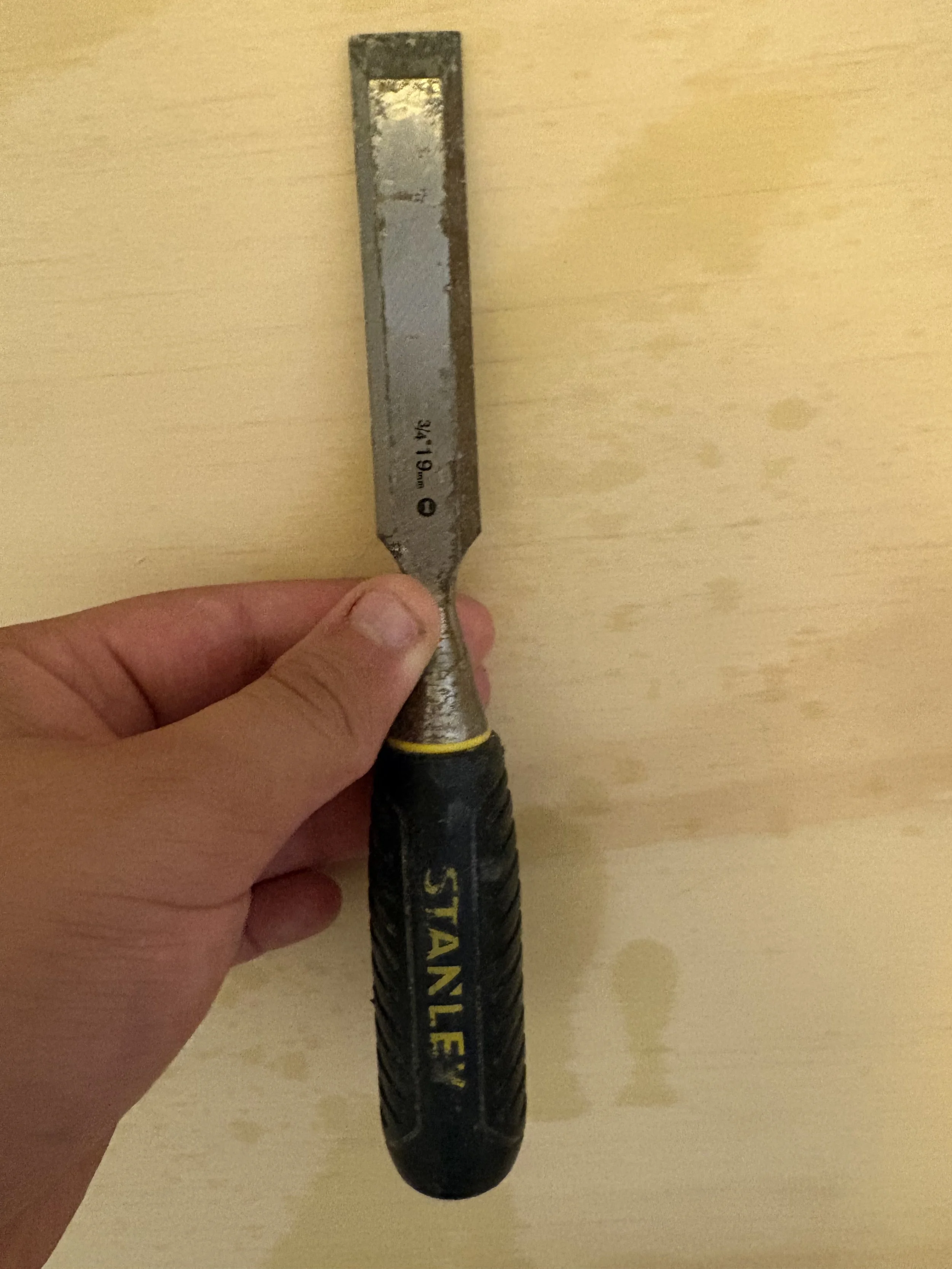 A person holding a large hammer with a black handle and a metal head with yellow and black lettering.