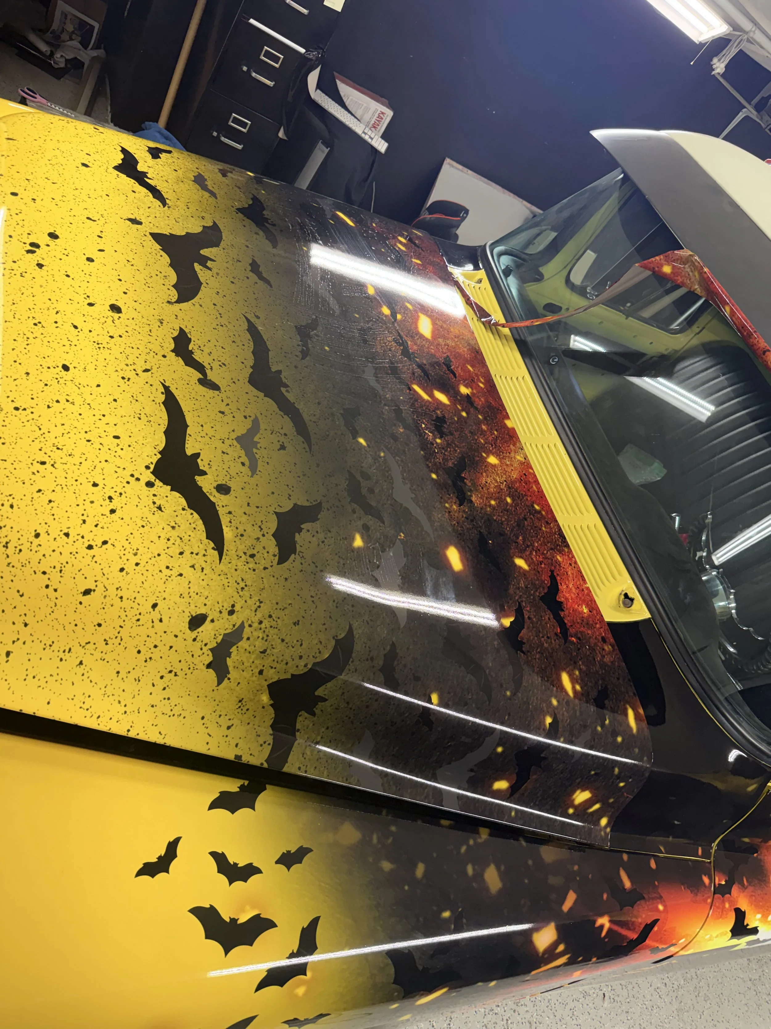 A vehicle with a Halloween-themed paint job featuring a large yellow pumpkin with black bats flying across it.