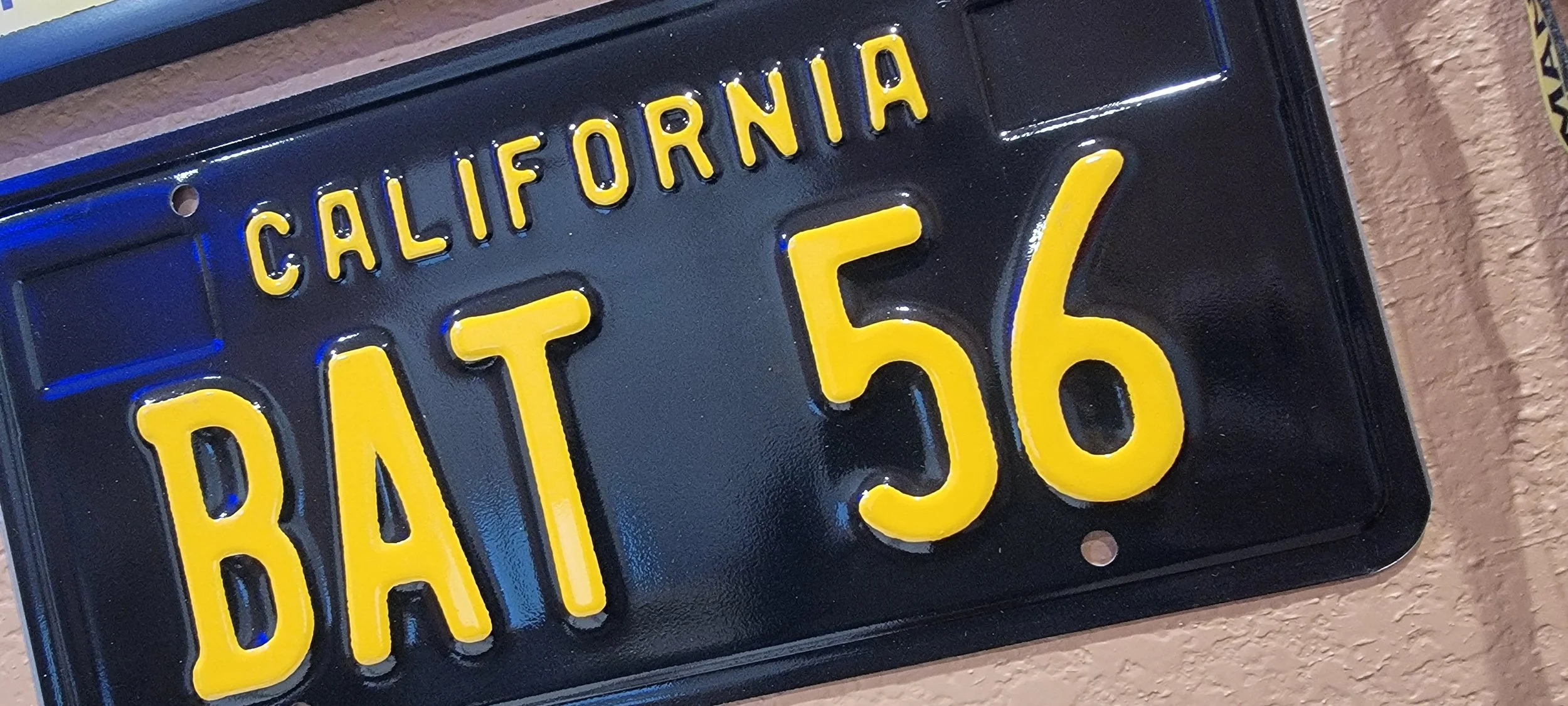 Close-up of a California license plate with yellow characters on a black background, reading 'BAM 56'.