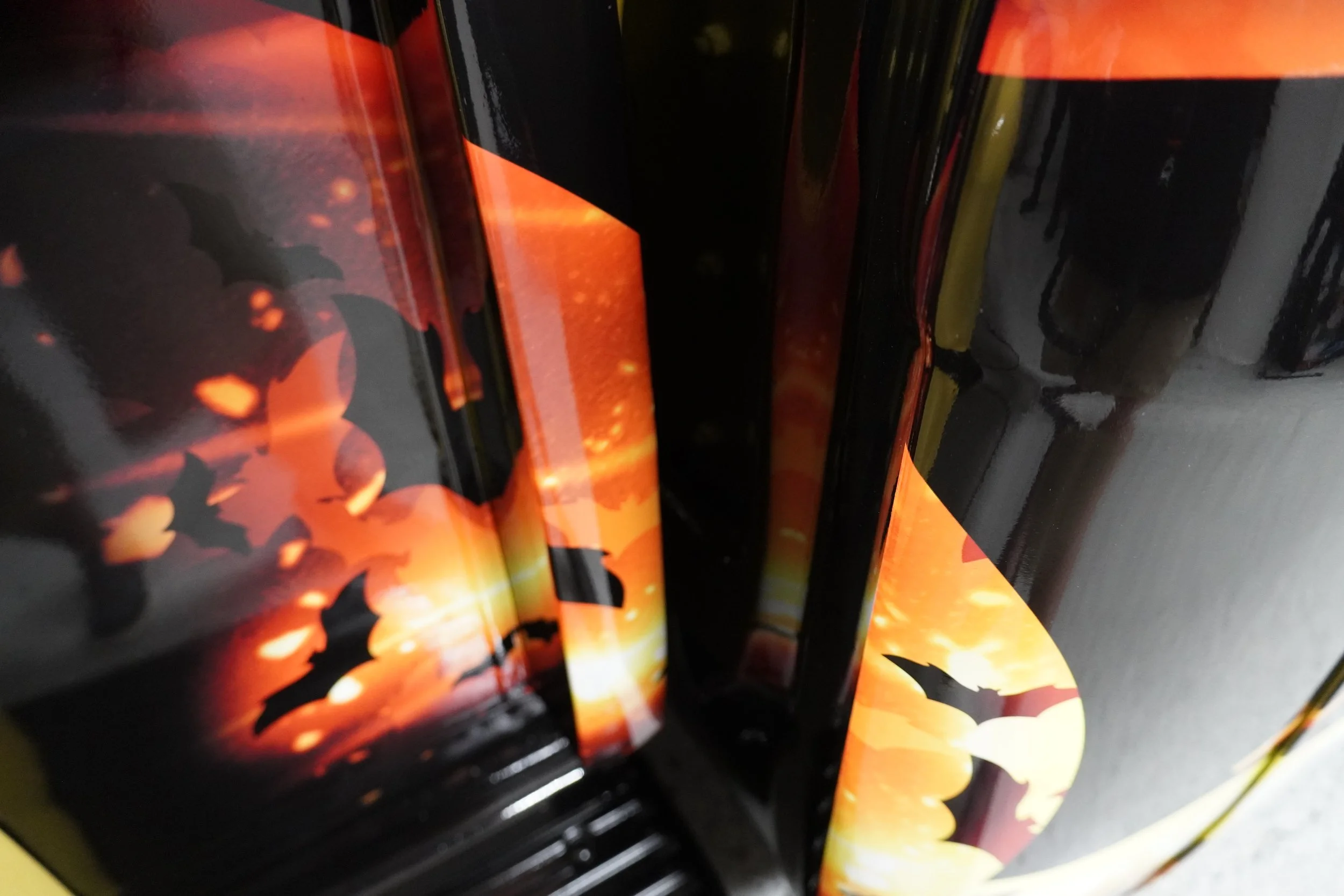 Close-up of a stack of Halloween-themed decorations or products with black, orange, and yellow colors, featuring bat shapes and a fiery background.
