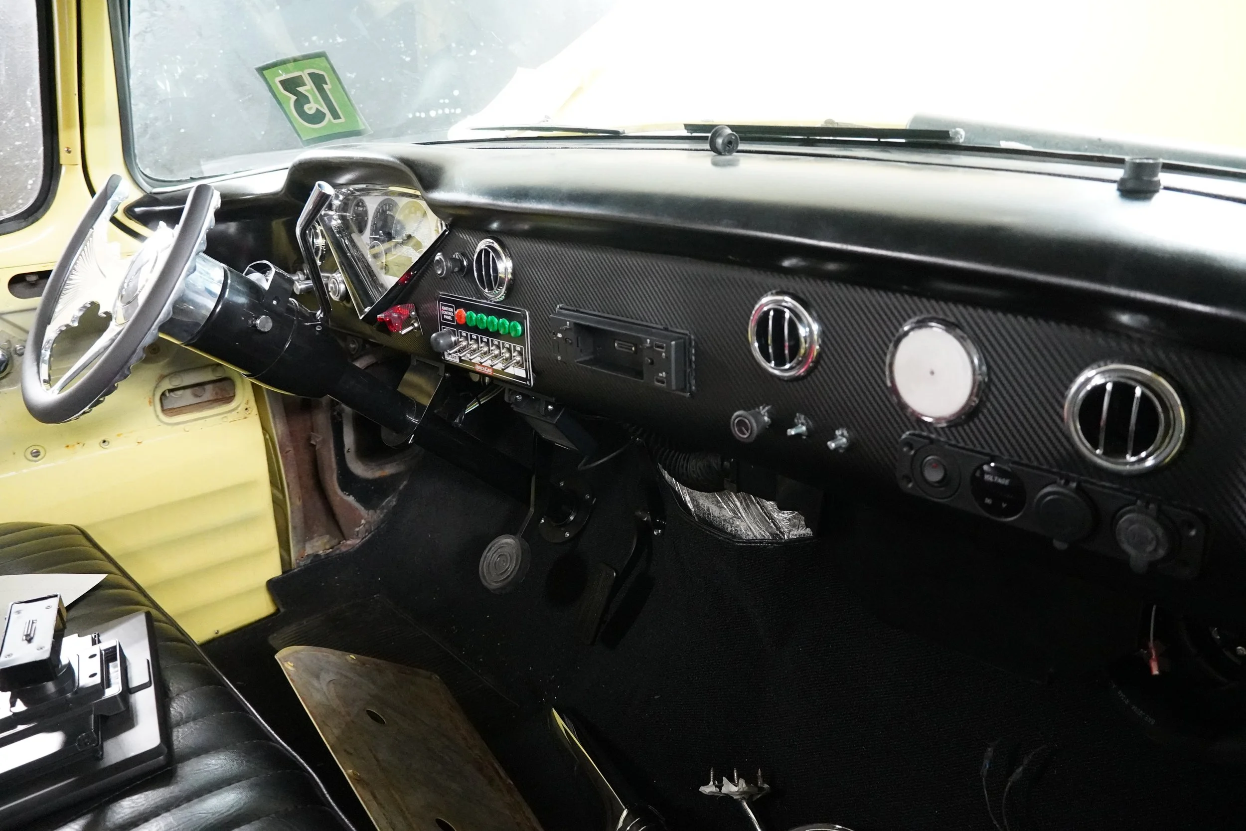 The interior of a vintage yellow vehicle, showing the dashboard with gauges, a steering wheel, and various switches and controls.