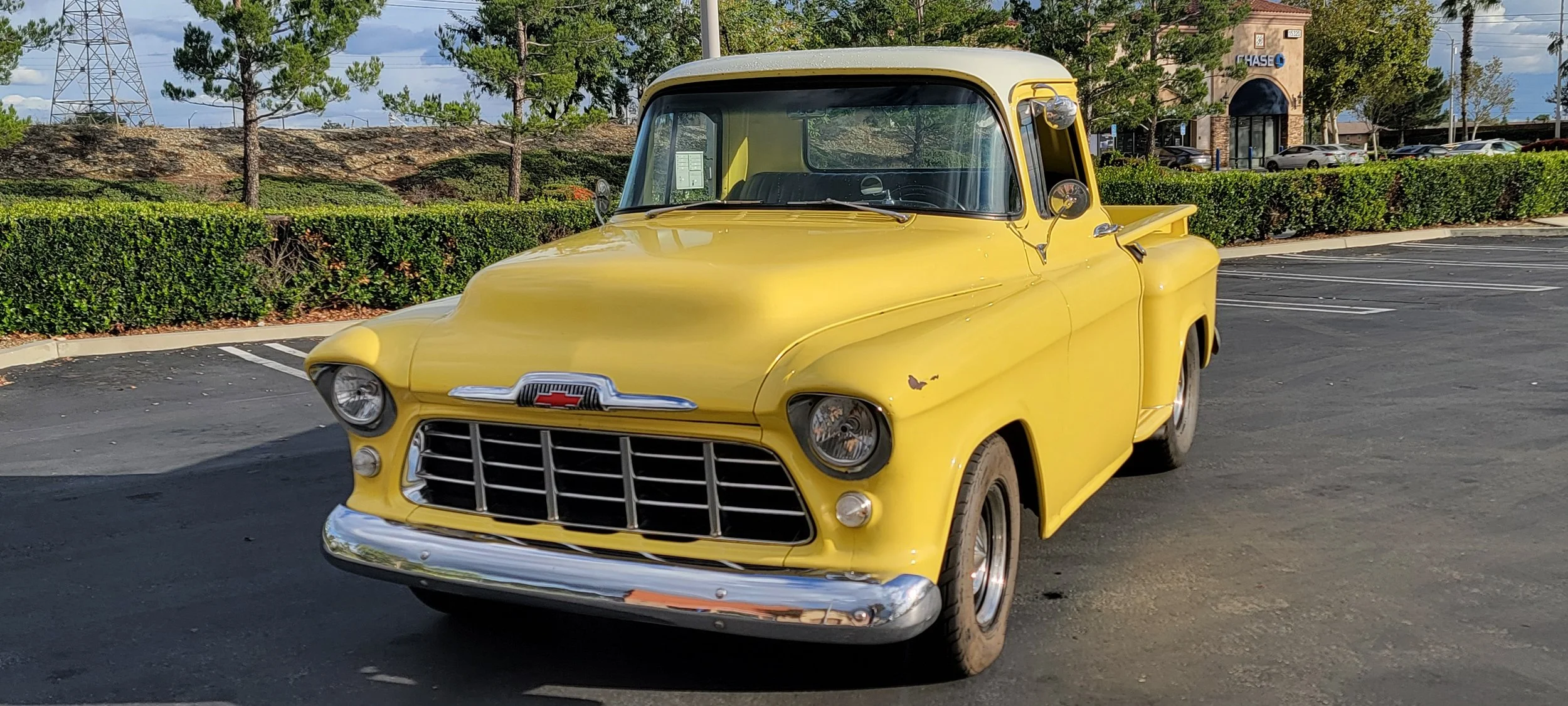 A vintage yellow Chevrolet pickup truck parked in an outdoor parking lot.