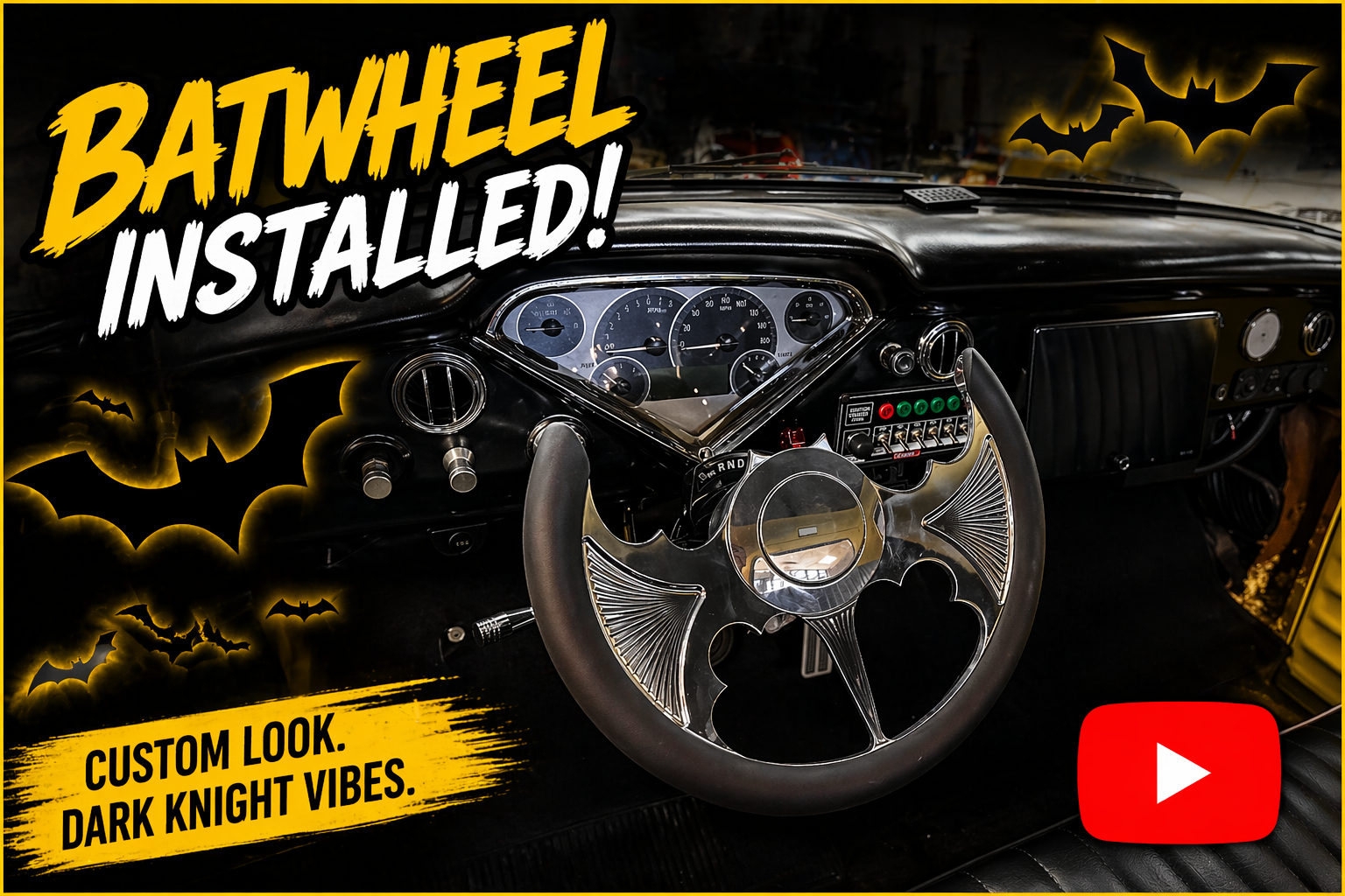 The interior of a car dashboard with a custom dark knight-themed steering wheel, accompanied by bat-shaped decorations and the message 'Batwheel Installed!' in bold yellow and white text, with a YouTube logo in the corner.