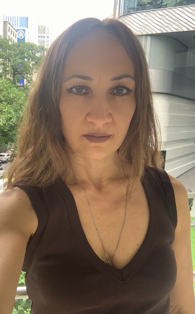 Woman with brown eyes, light brown hair and a thin silver necklace at Bangkok city background.