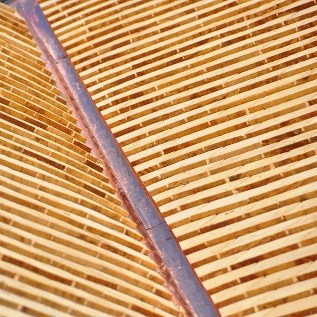 Close-up of a curved structure made of wooden slats attached to a metal beam.