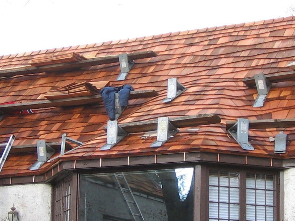 Roof being repaired with tiles removed and workers installing new tiles.