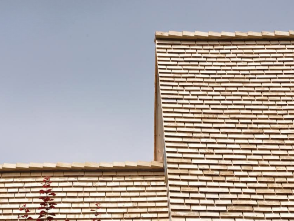 Close-up of a house's wooden shingle roof against a clear blue sky.