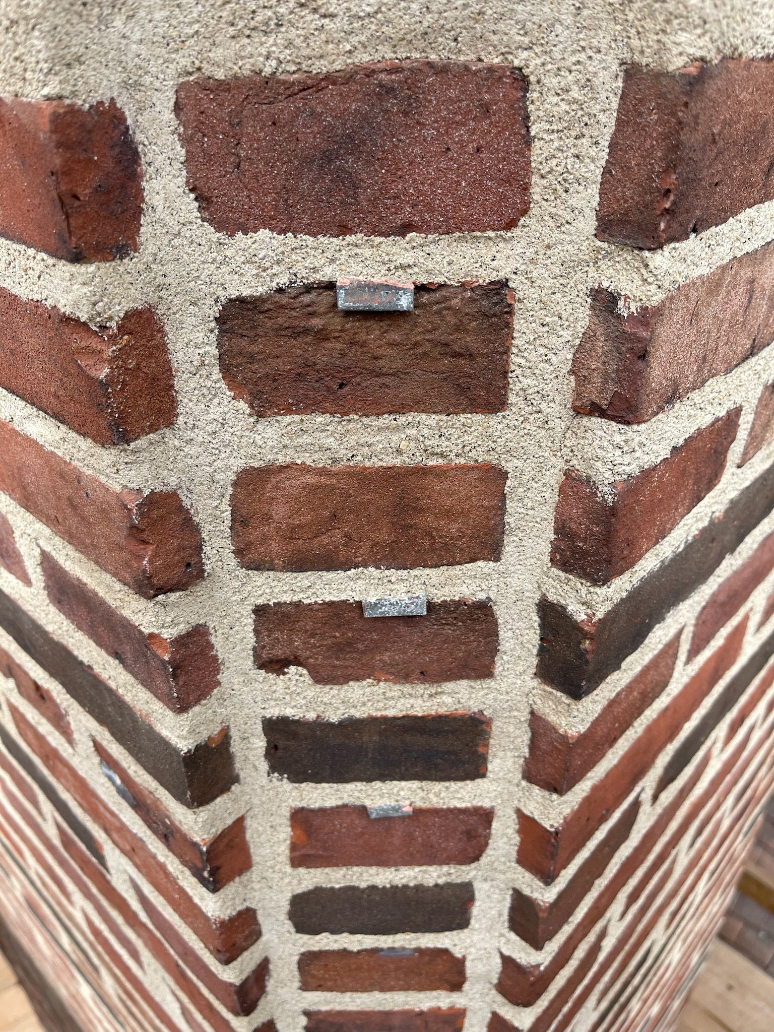 Close-up of a corner of a brick wall with light-colored mortar, showing the detailed texture and arrangement of red bricks.