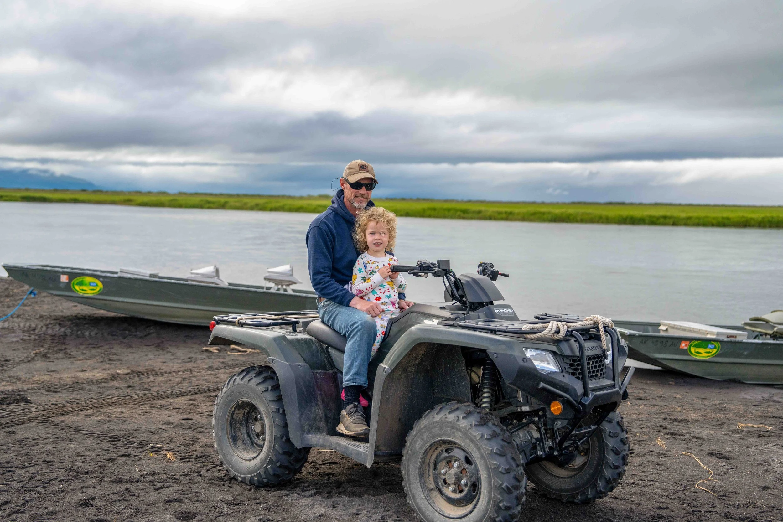 A guest riding an ATV with a child on the beach at Lava Creek Lodge