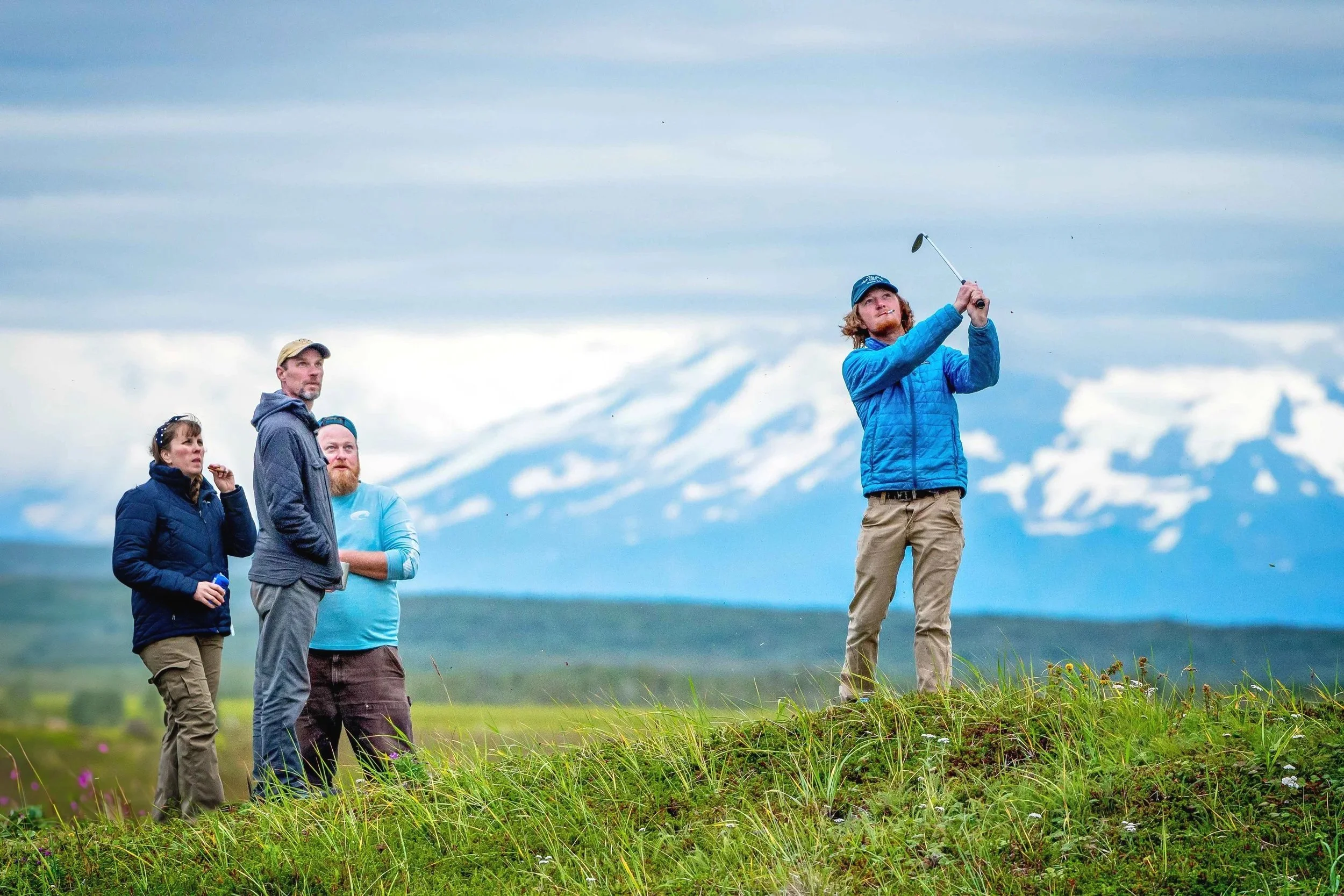 Guests playing golf on the tundra with mountains in the background at Lava Creek Lodge.