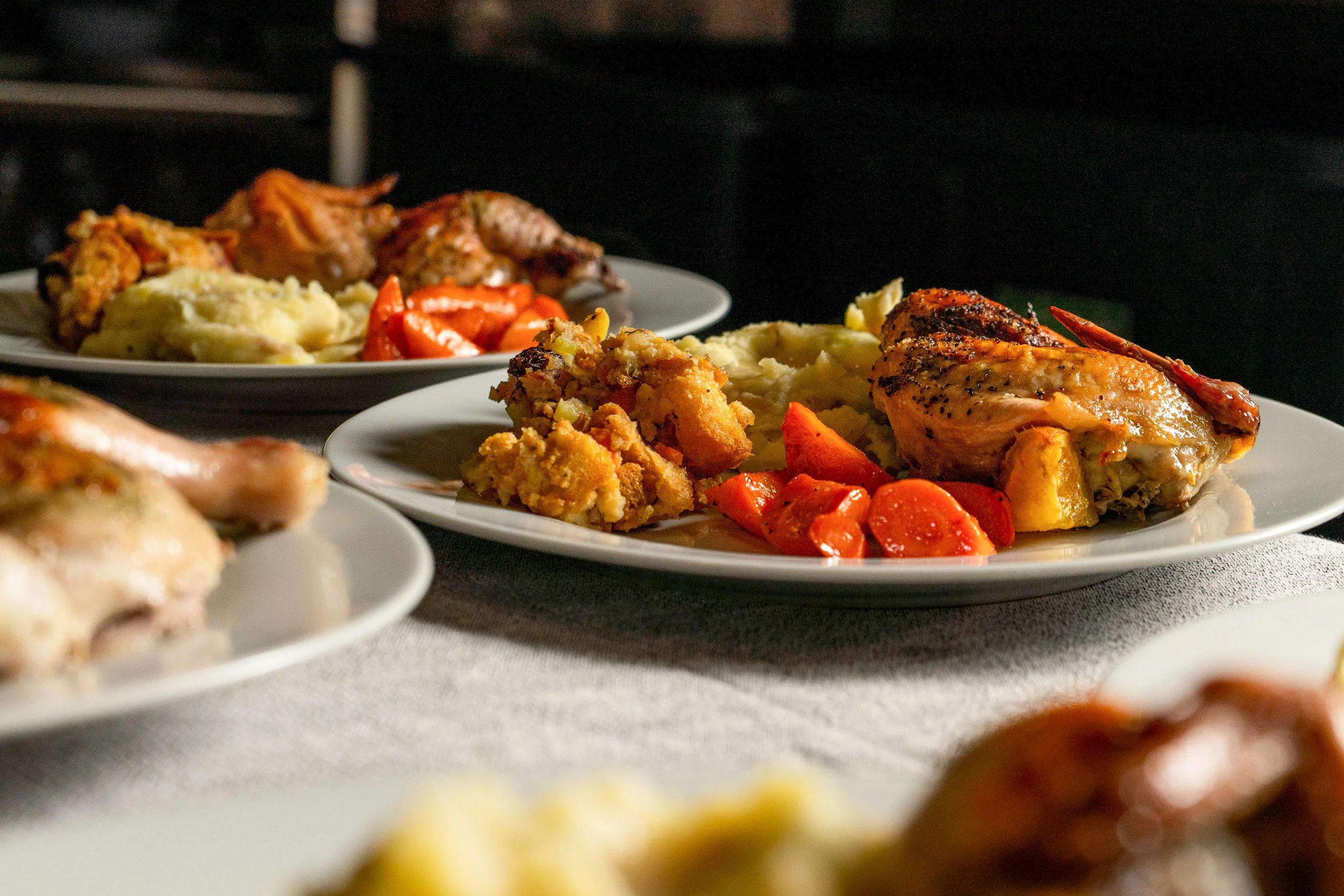 Plates of cooked food including mashed potatoes, roasted chicken, and vegetables, set against a dark background at Lava Creek Lodge.