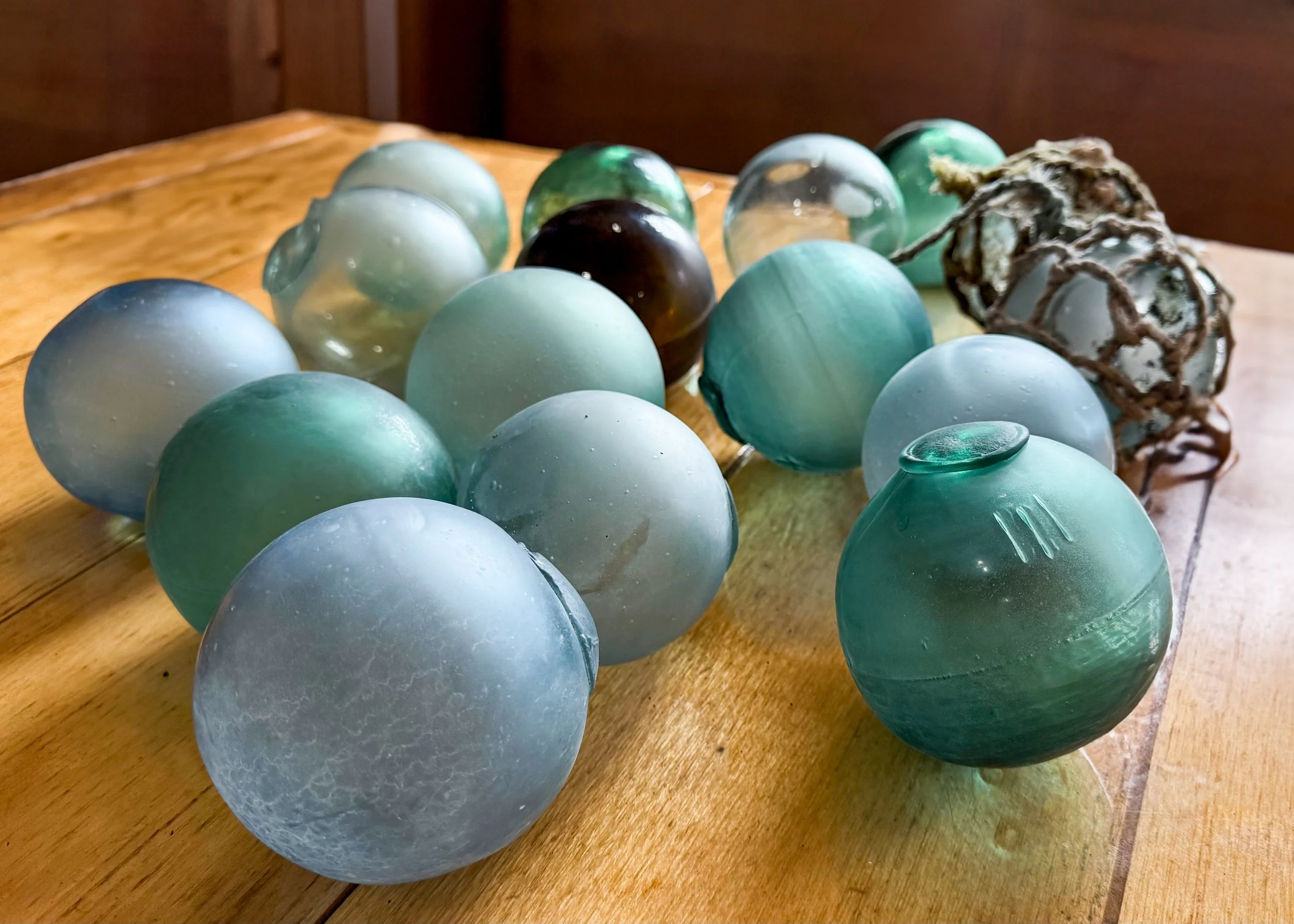 Collection of Japanese glass fishing floats on a wooden surface at Lava Creek Lodge.