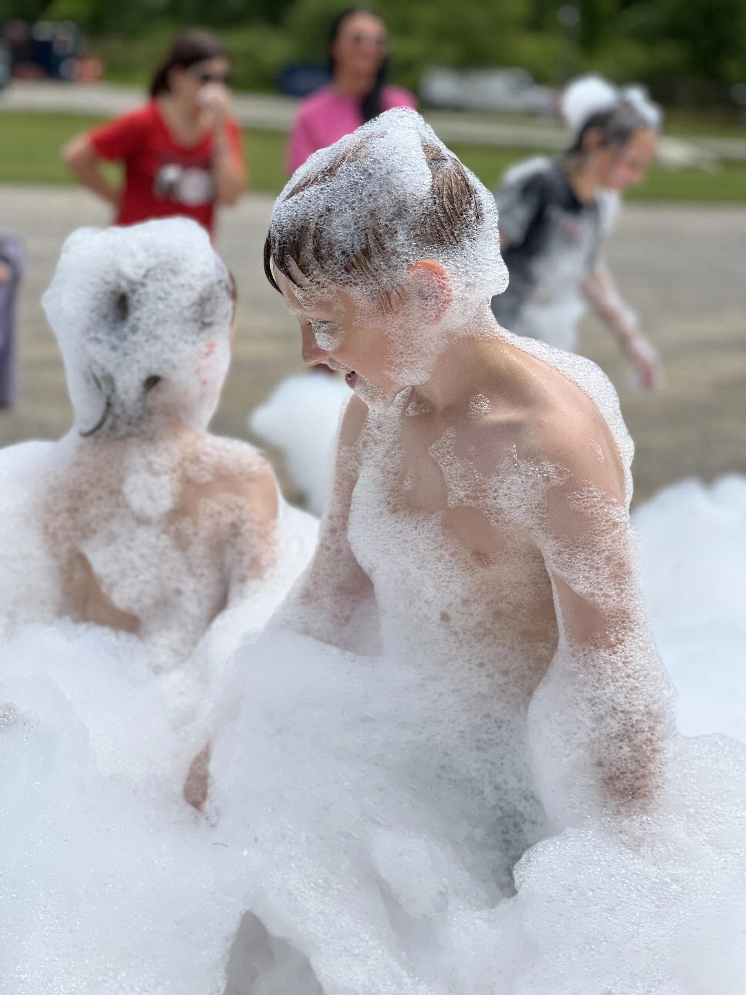 a child smiling standing in a pile of foam