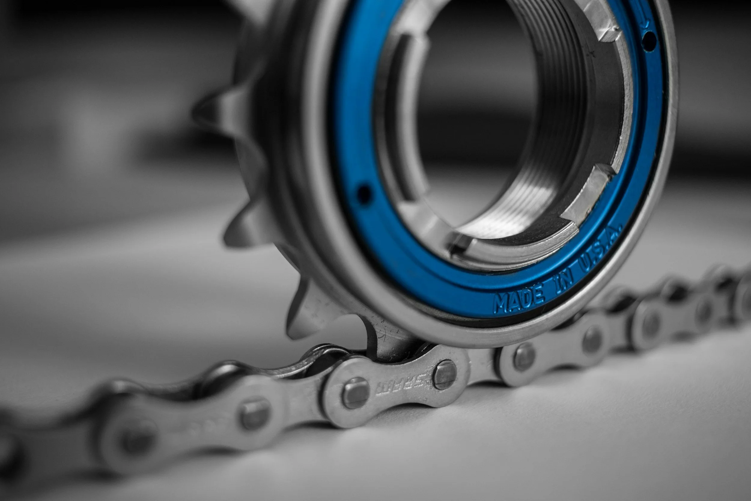 Close-up of a bicycle chain and bottom bracket with a blue outer ring.