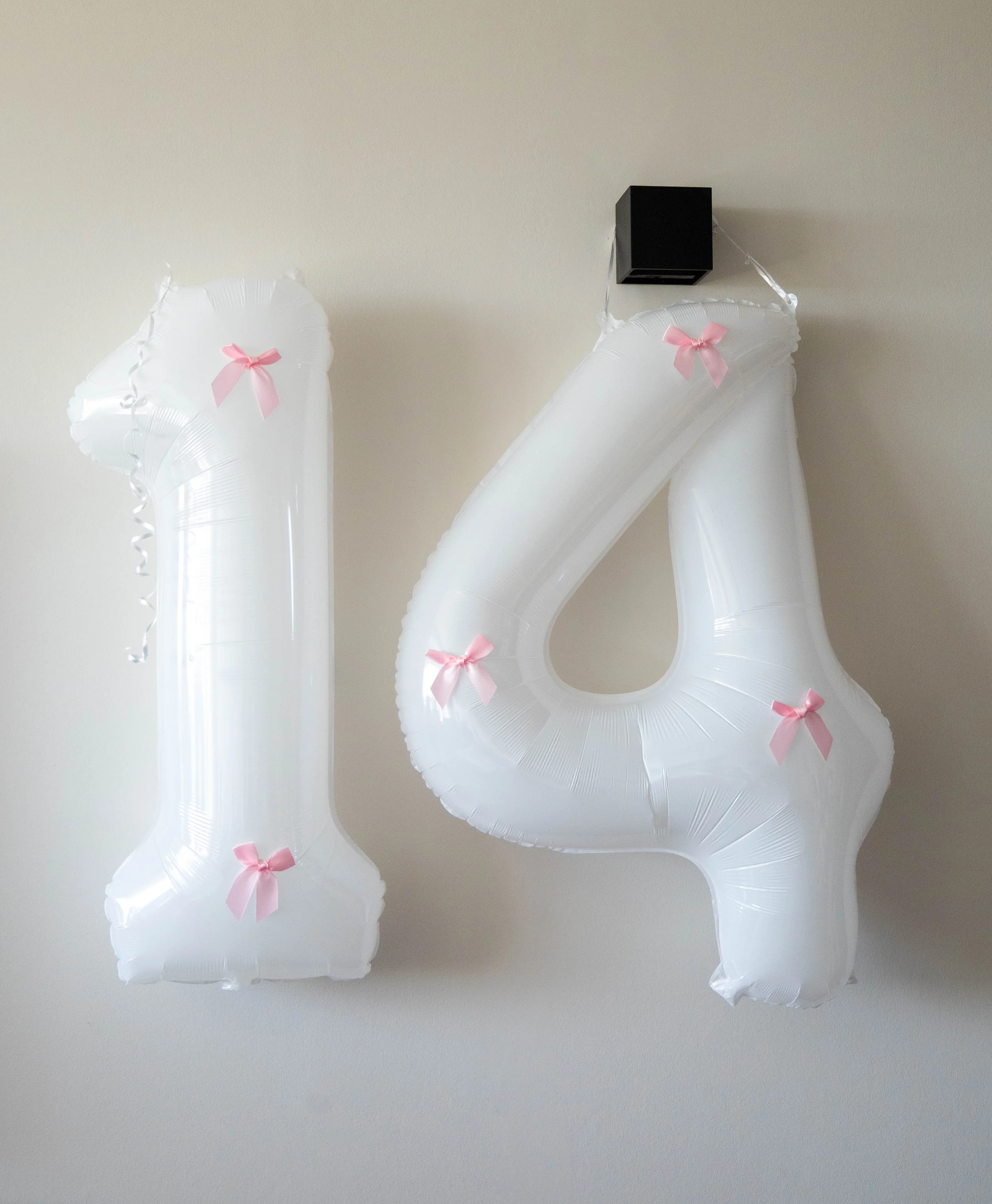 White balloons with pink bows attached to them, arranged against a plain white background.