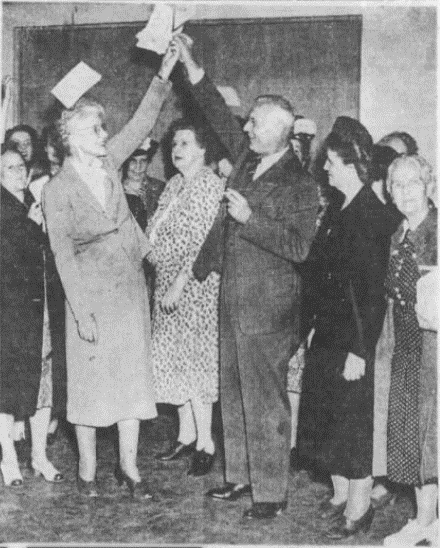 Wilkinson’s arm held aloft in victory while her supporters toss pamphlets in the air to celebrate her 1948 provincial election victory. Calgary Herald, 18 August 1948.