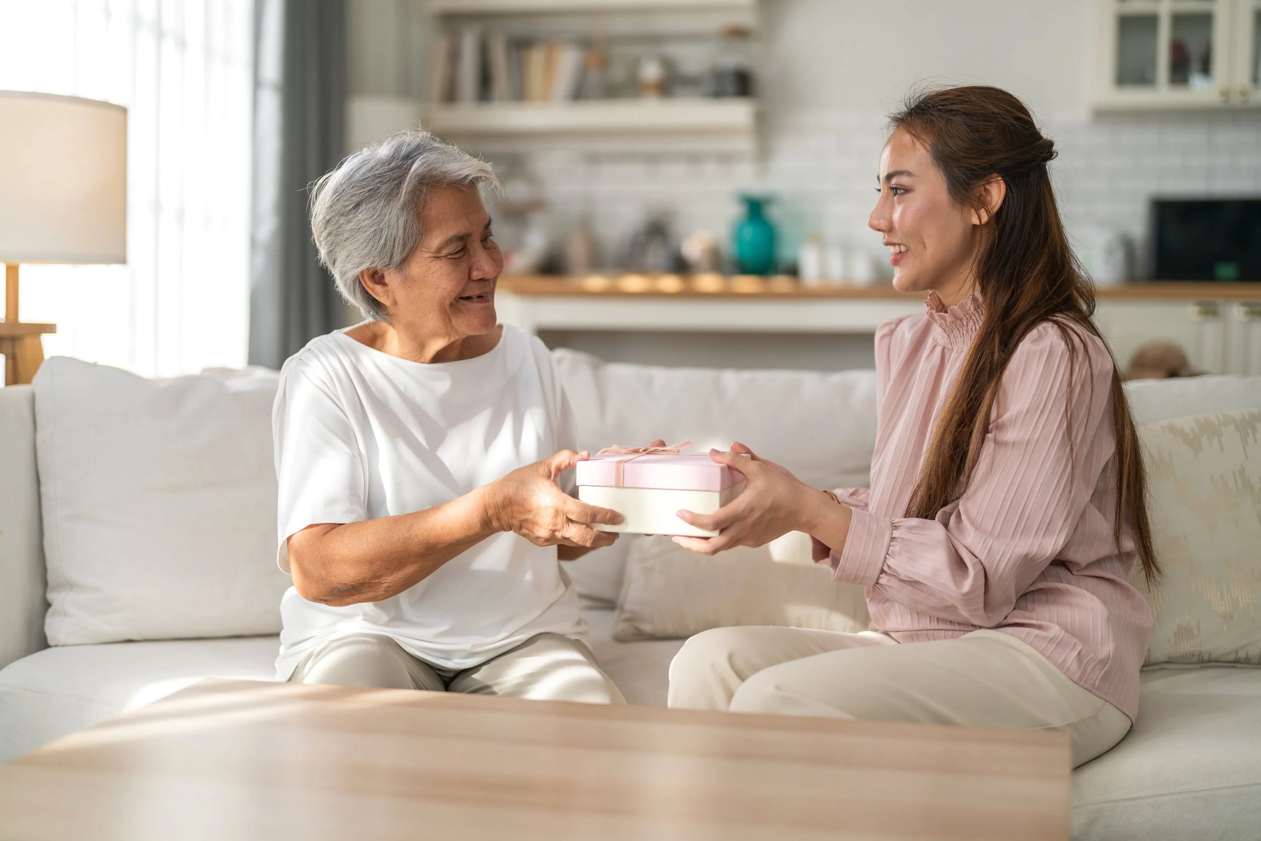 Grandmother receiving a thoughtful Grandparents Day gift from her granddaughter at home