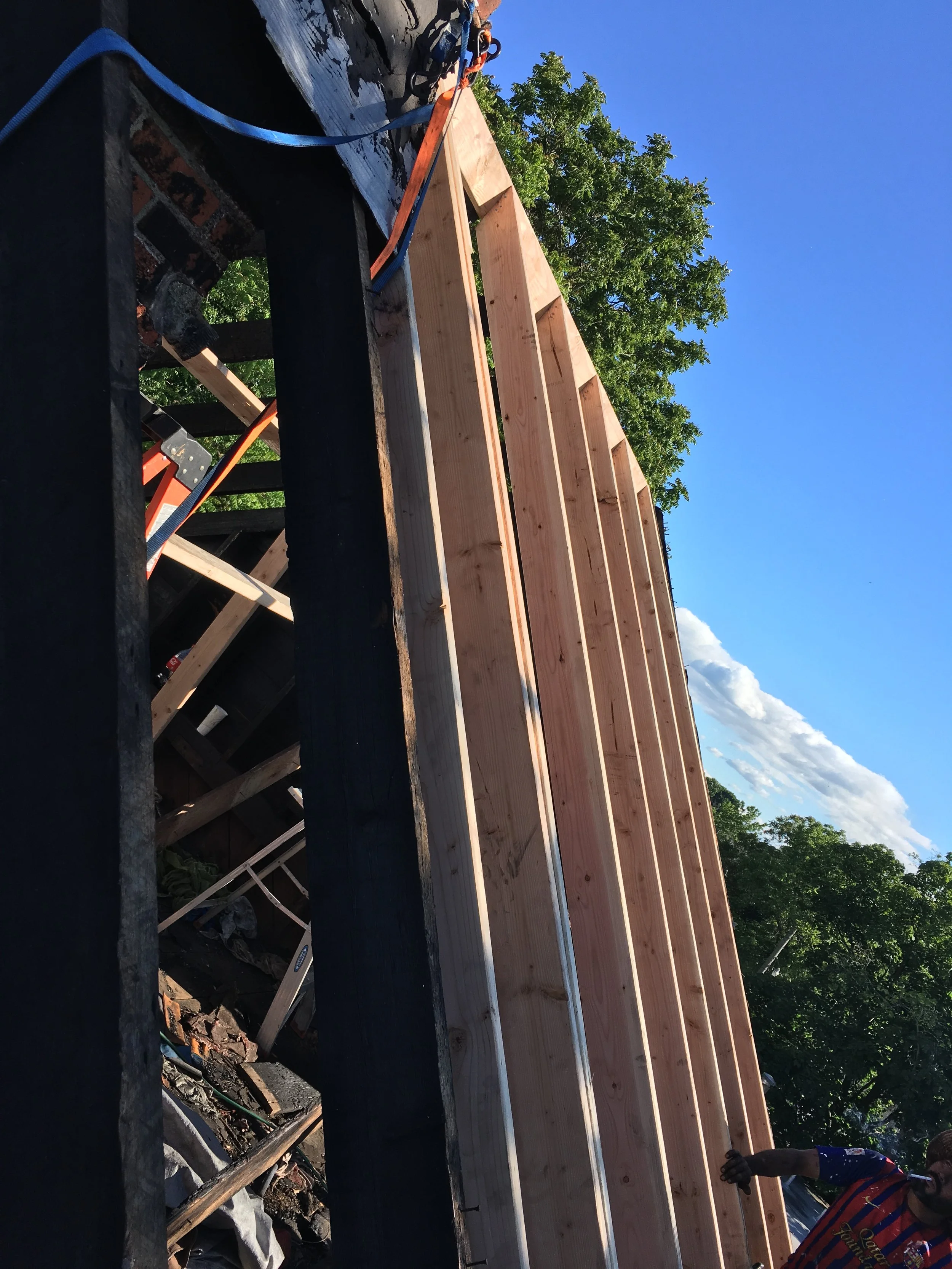 Workers replacing shingles on a house roof during daylight.