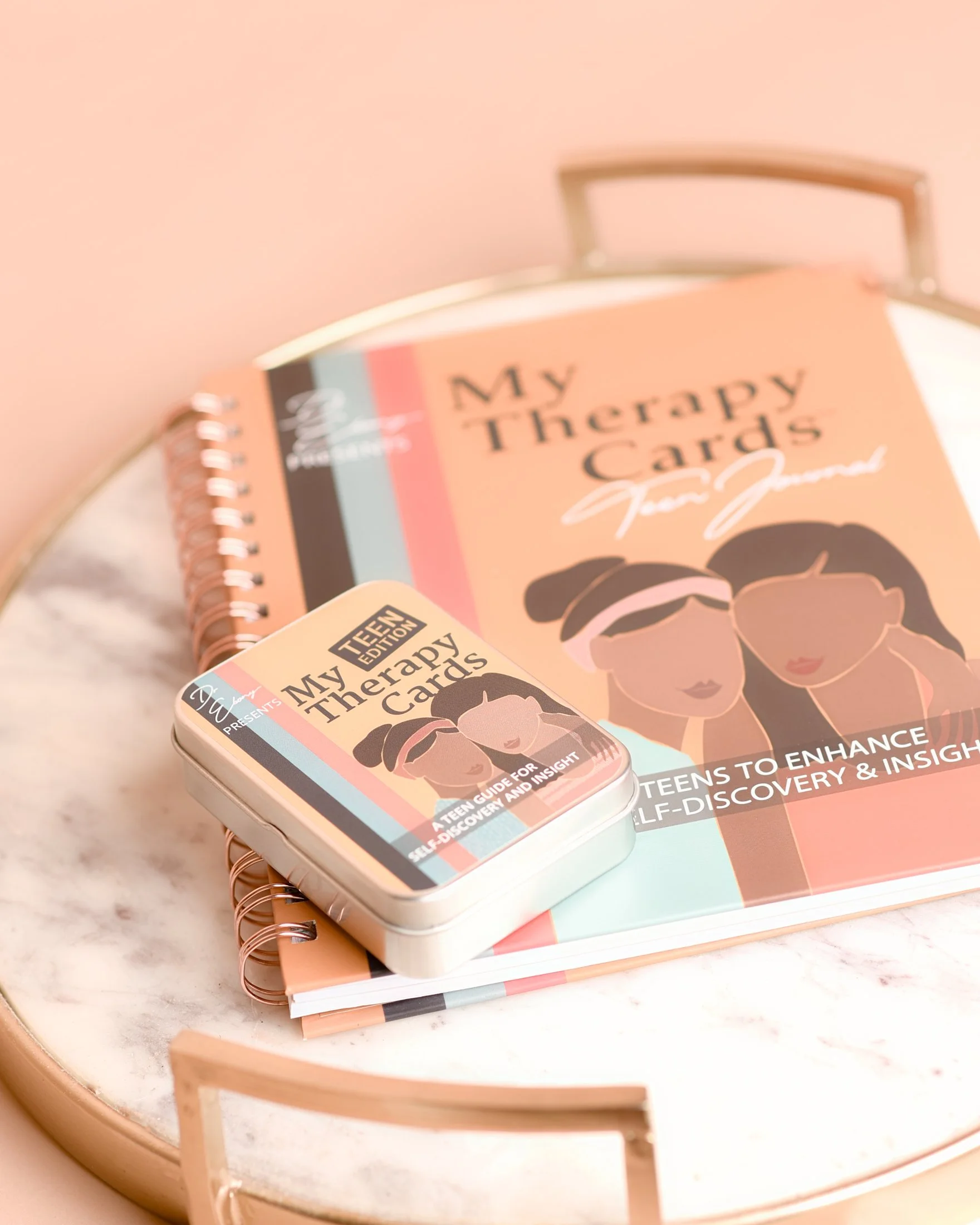 A box and a notebook titled "My Therapy Cards" resting on a light-colored marble table, with a pink chair in the background.