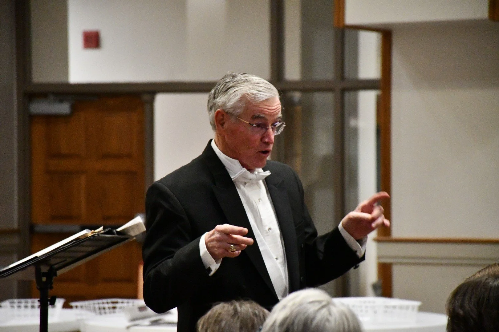 Photograph of Steve Eubank in tuxedo addressing the choir before concert.