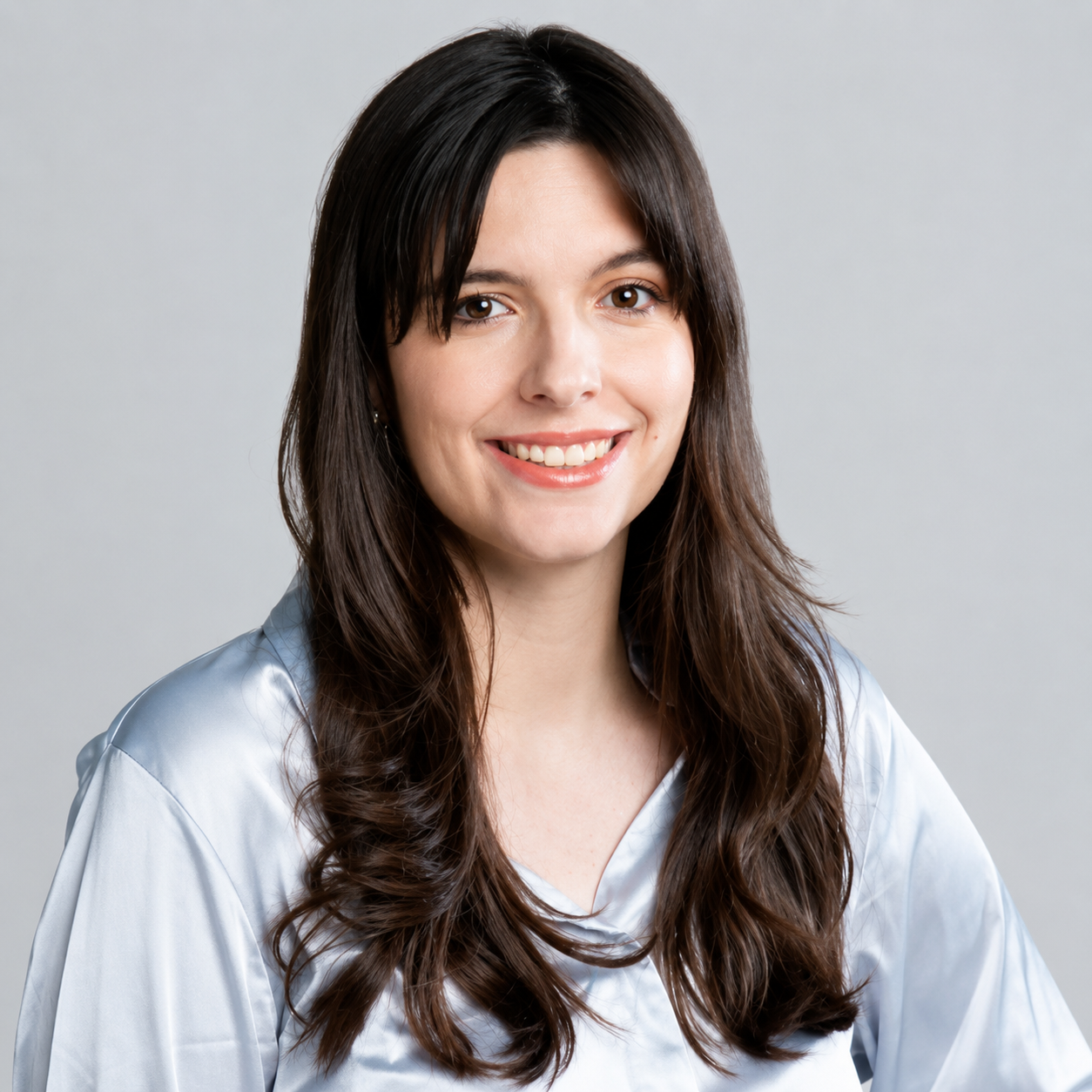 A portrait of Miriam Johnston, Interior Decorator at New Life Staging & Styling. She is smiling and has long brown hair wearing a light blue blouse, against a plain gray background.
