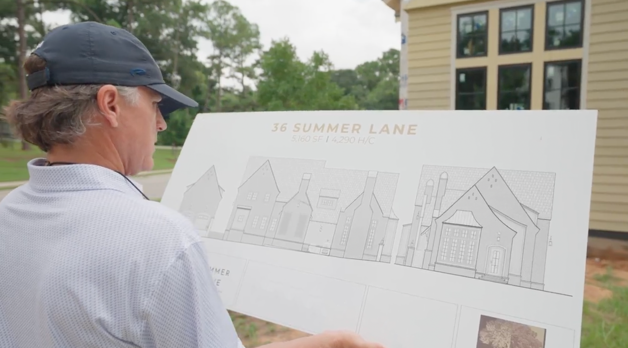 A man looking at a sign with house floor plans during daytime outdoors.