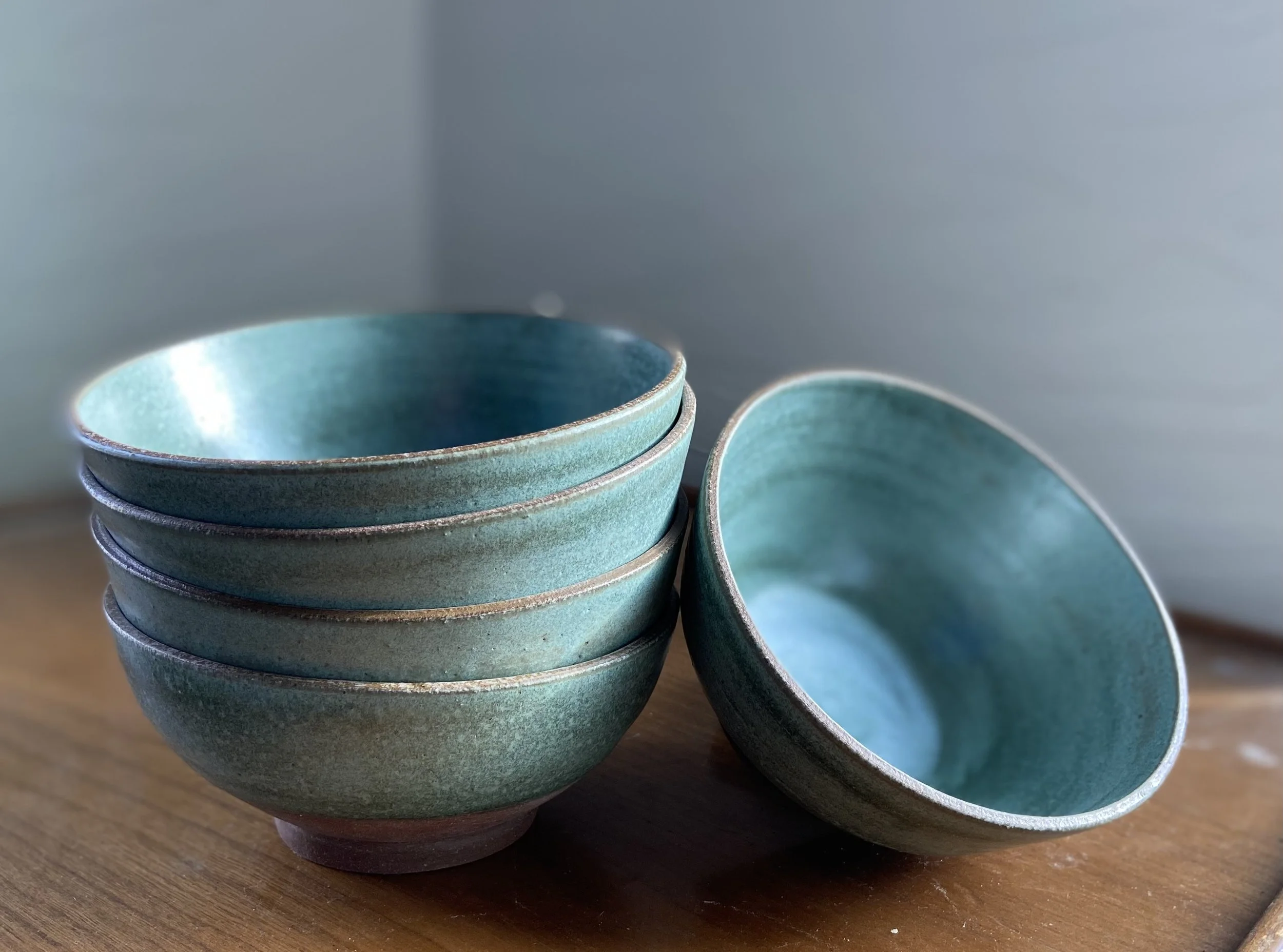 set of dinner bowls stacked. Red clay bowls with a turquoise glaze