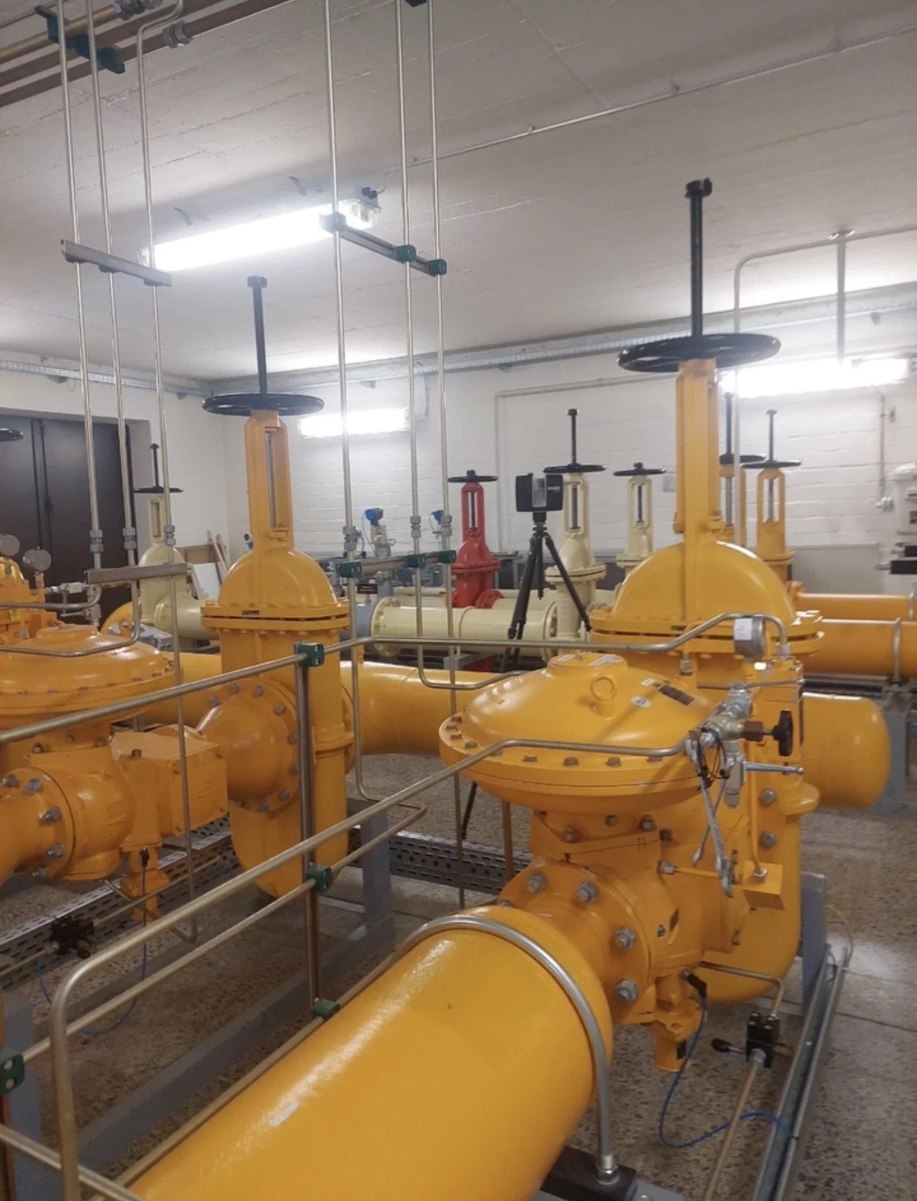Technische Ingenieuranlage mit gelben Rohrleitungen und Armaturen in einem Industrie- oder Wasserkraftwerk.