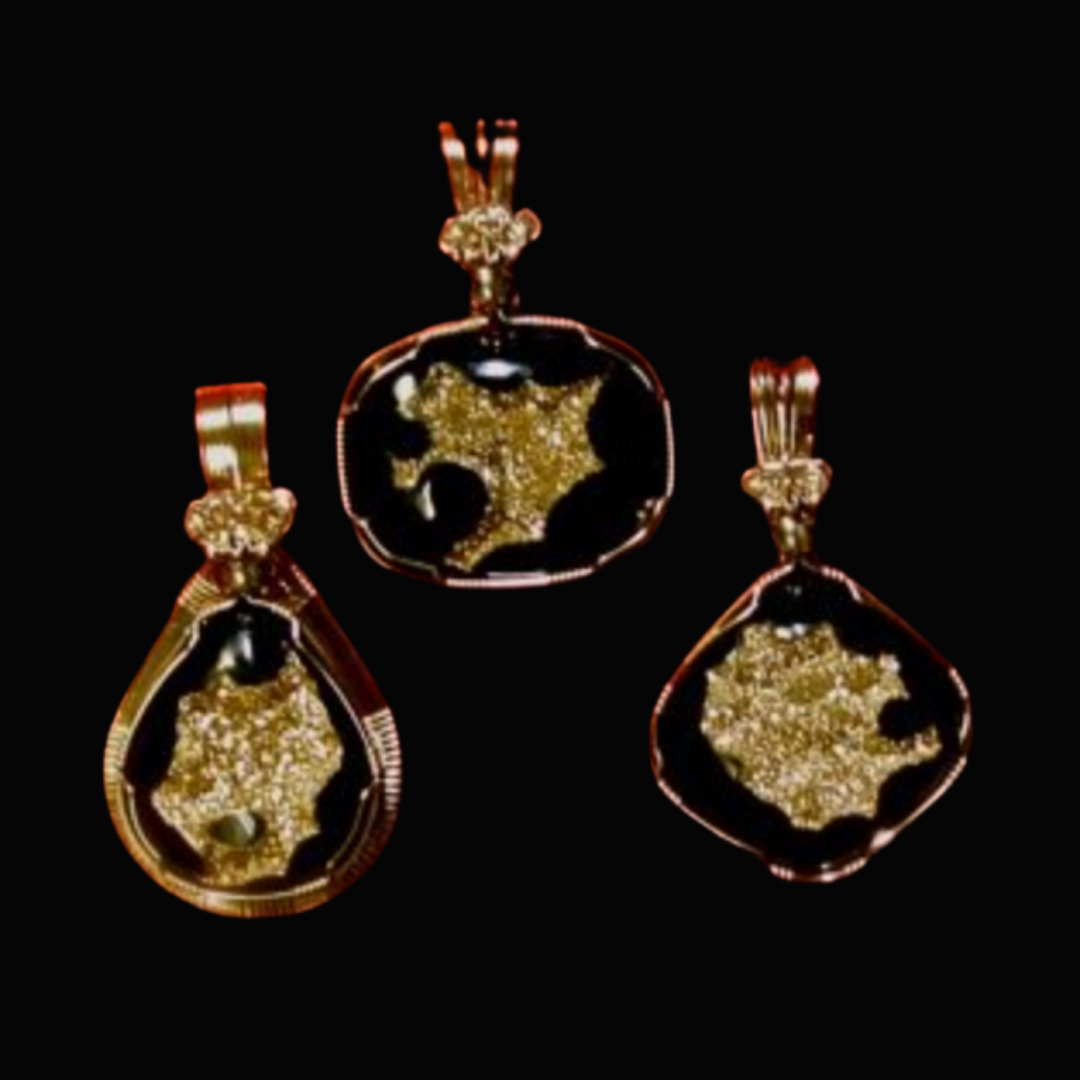 Three gold pendant necklaces with glittering black and gold designs on a black background.