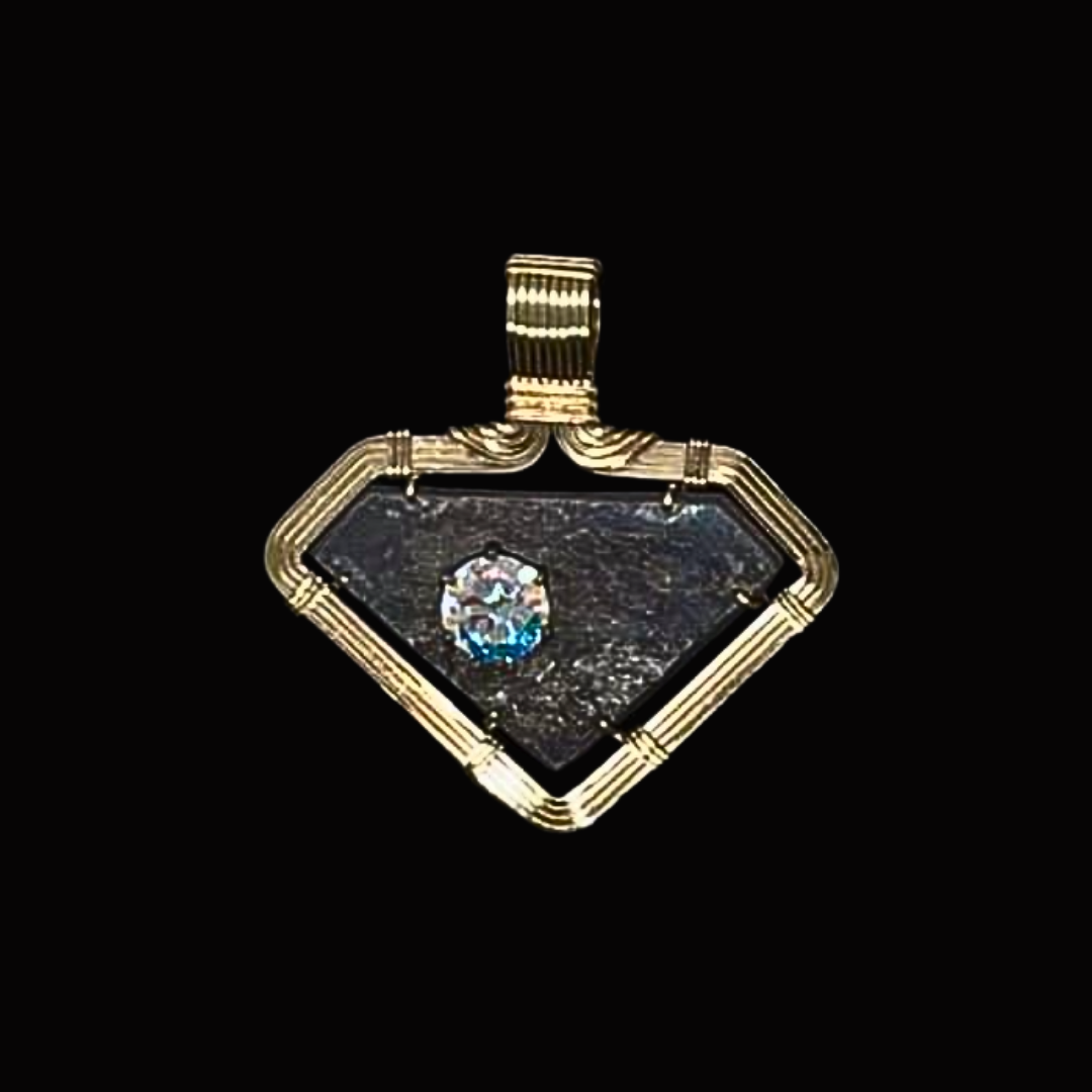A gold pendant featuring a diamond-shaped design with a small gemstone in the center, set against a black background.