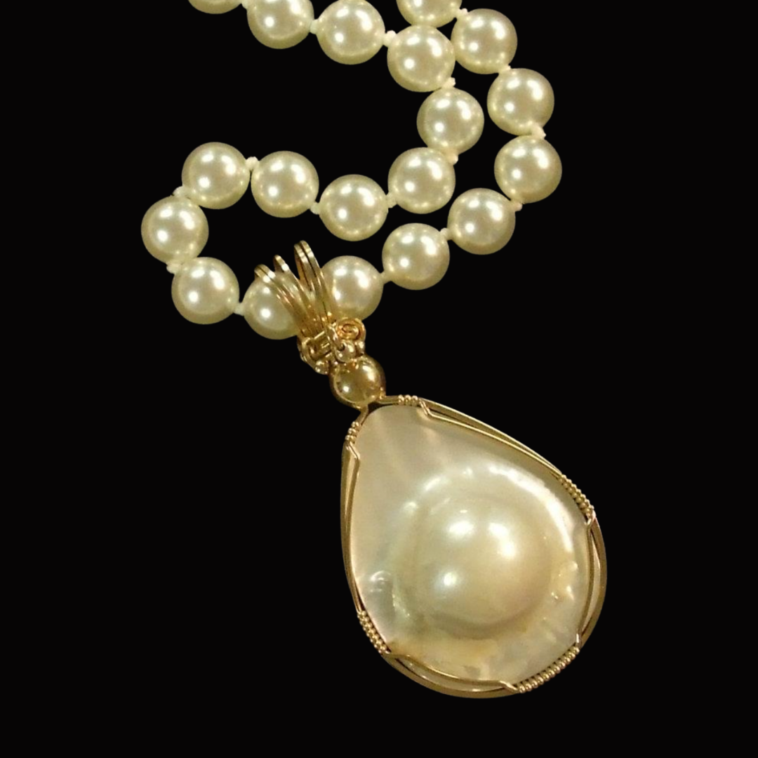 Elegant pearl necklace with a large pearl pendant on a gold setting, displayed against a black background.