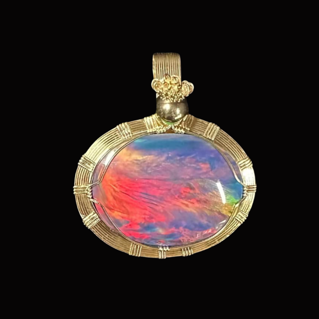 Gold pendant with a large oval opal gemstone reflecting colorful skies, set against a black background.