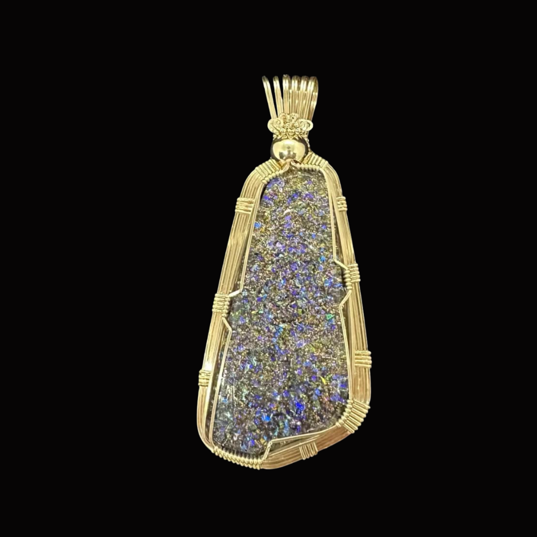Gold pendant with shaped gold frame and a colorful, iridescent inner surface against a black background.