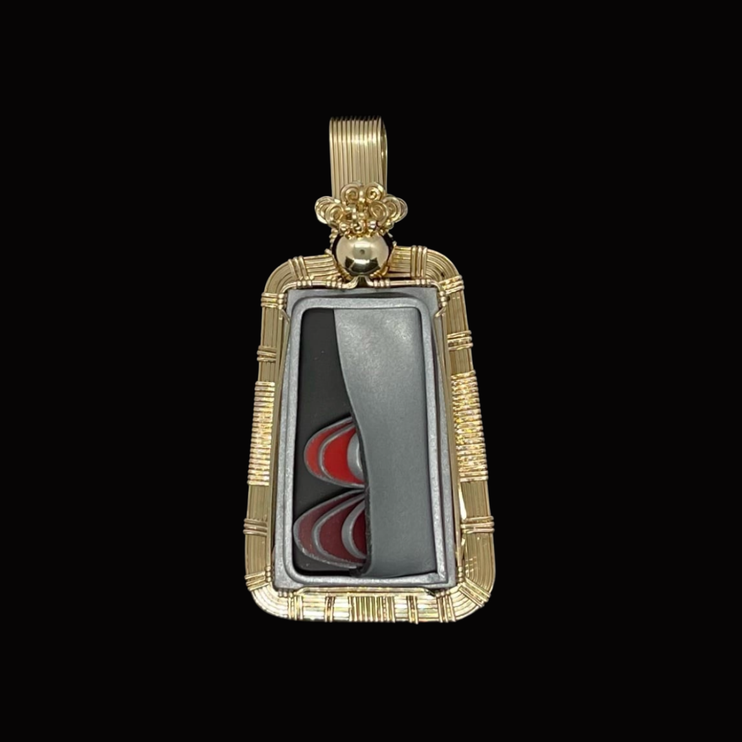 Gold pendant with a black and red dartboard design inside, surrounded by a gold frame.