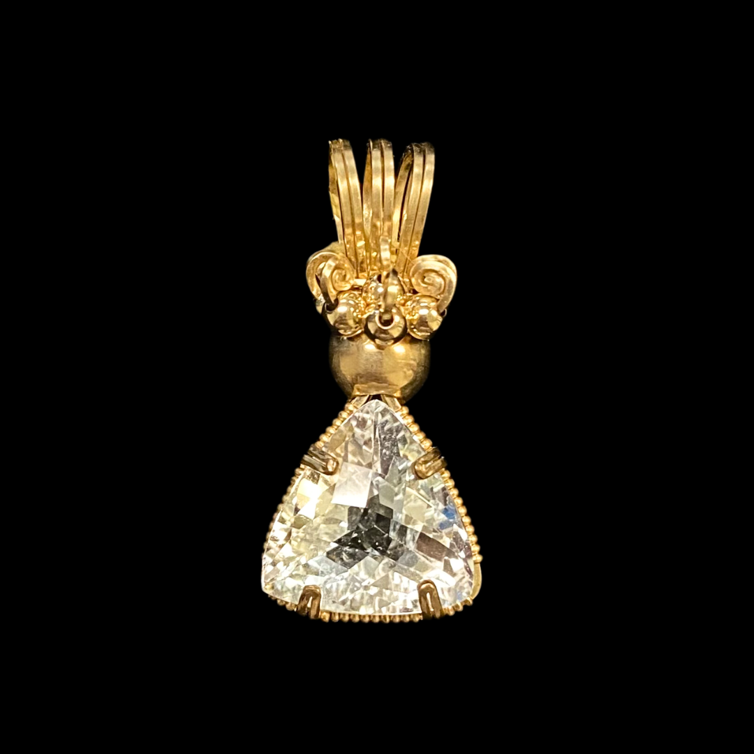 Gold pendant with a large, triangular-cut clear gemstone on a black background.